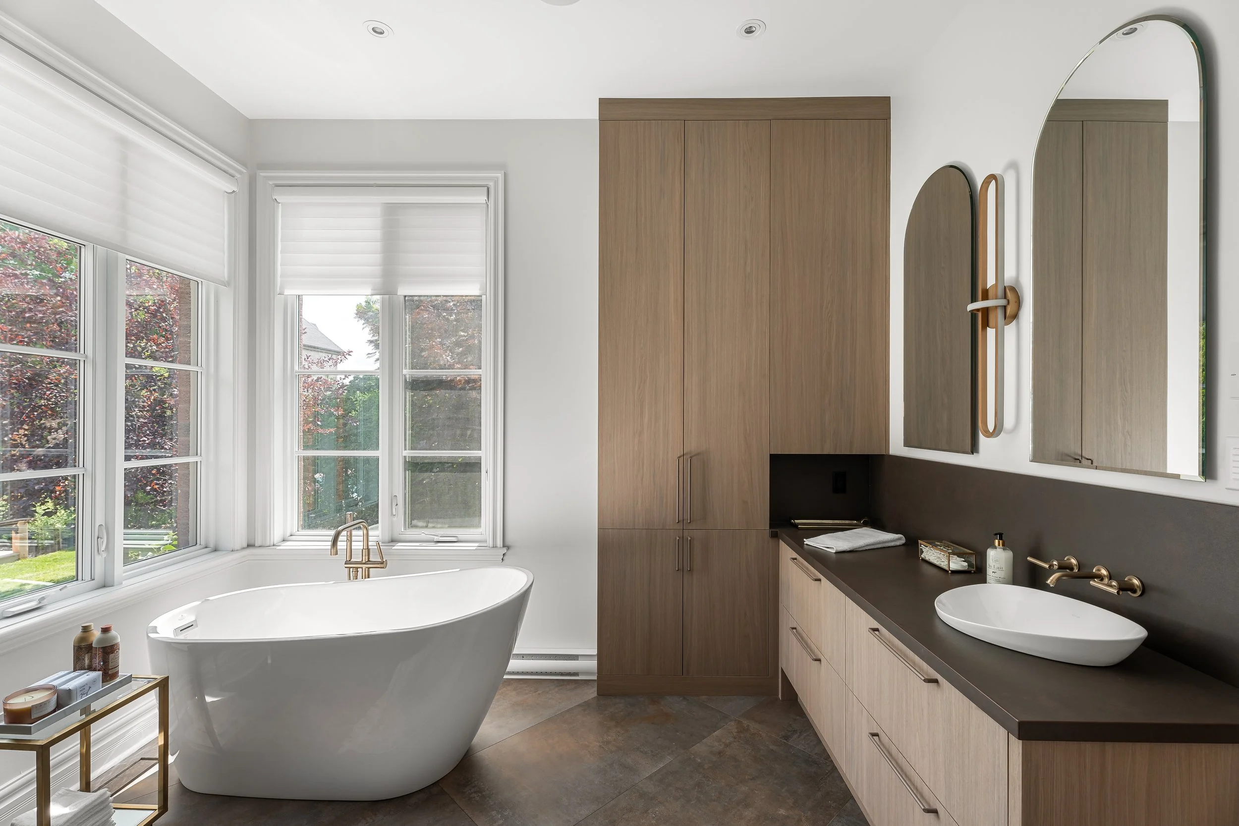 High-end bathroom renovation in Brossard near Montreal featuring custom wood cabinetry, freestanding tub, and double mirrors.
