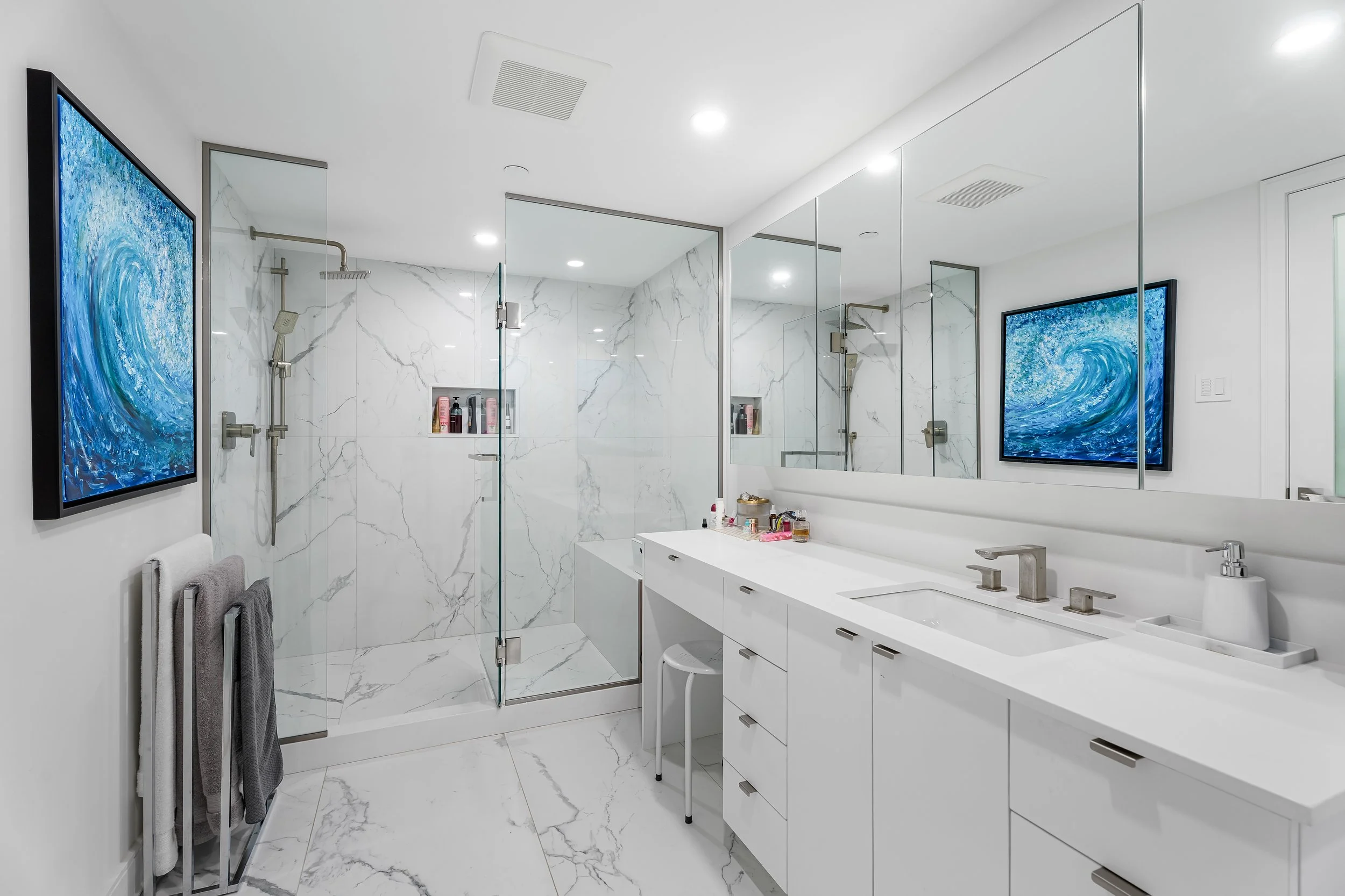 Luxury master bathroom renovation on Atwater in Montreal with integrated makeup station and large custom shower with integrated niche and glass doors. 