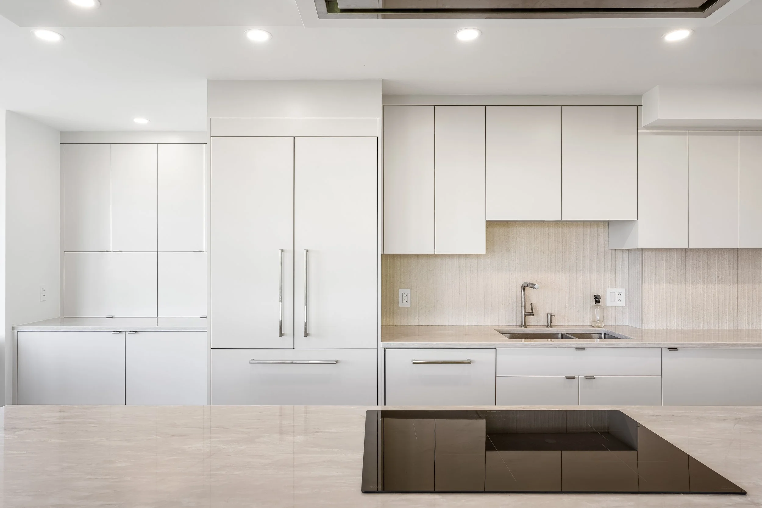 Luxury residential condo renovation in Montreal featuring integrated fridge, custom lacquered cabinets and quartz countertops. 