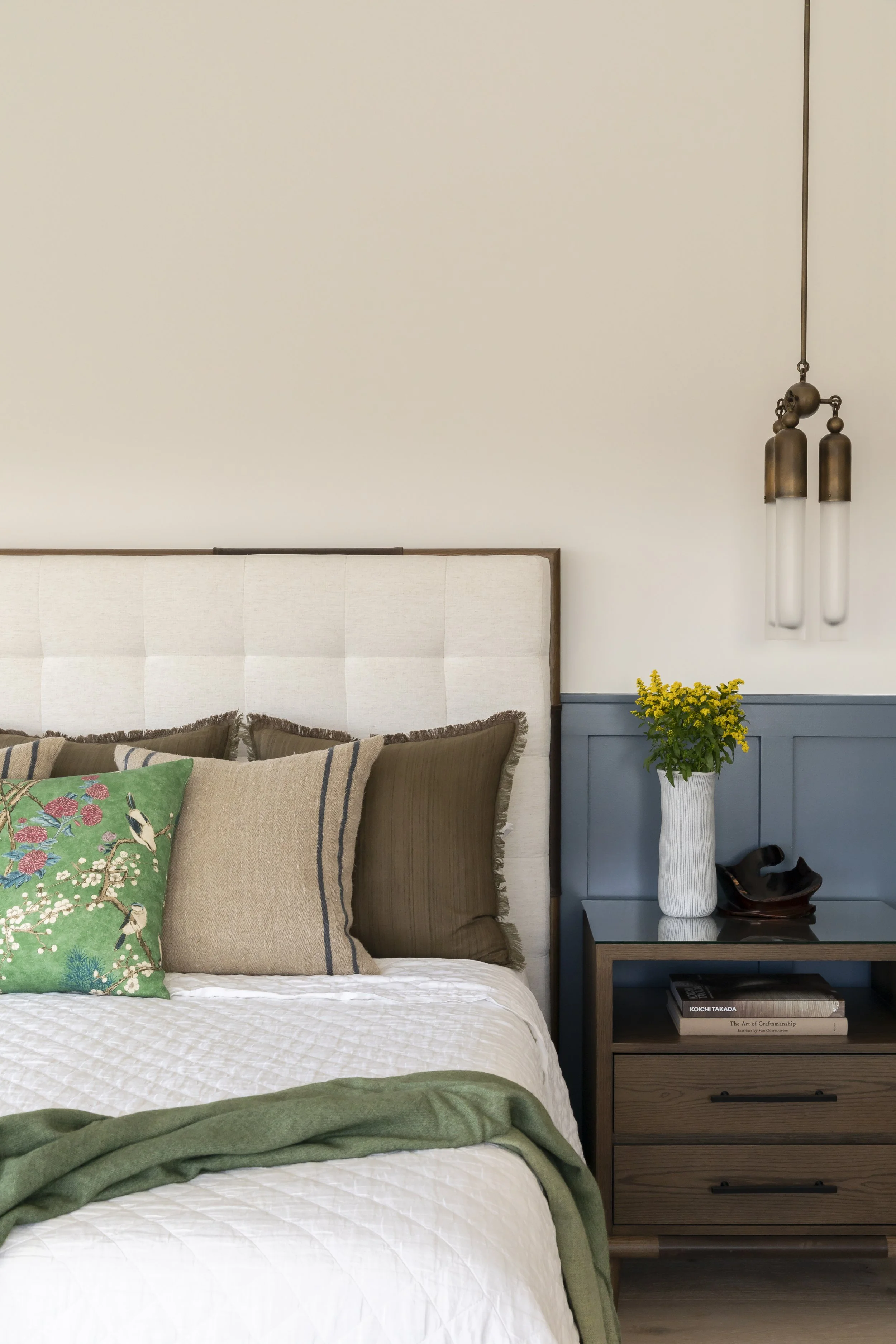 Solana Beach, CA bedroom design featuring custom wall paneling, layered bedding, and sculptural bedside lighting in a calm, coastal-inspired space by Anne Flynn Designs.