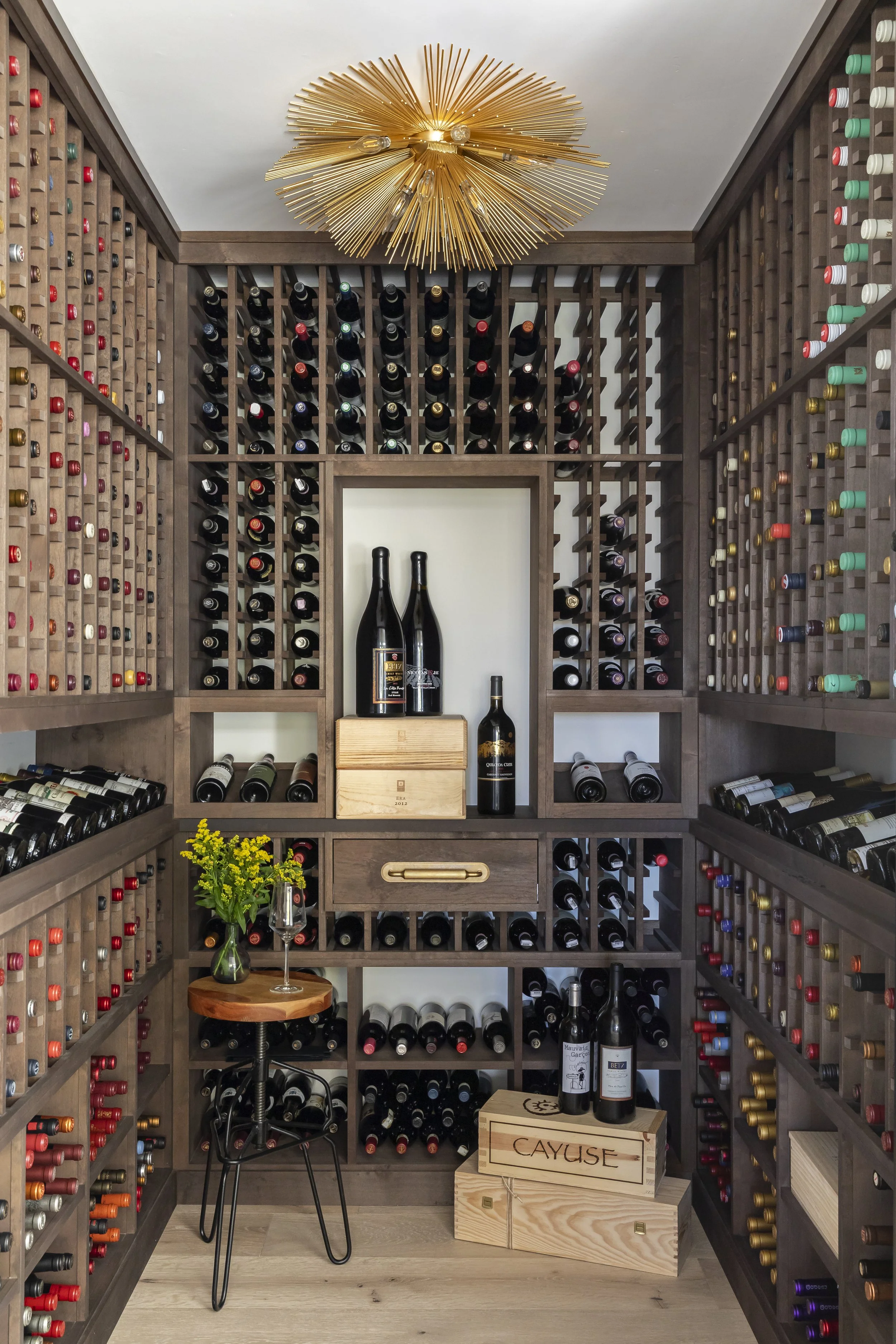 Solana Beach, CA custom wine room design featuring floor-to-ceiling wood wine storage, a sculptural chandelier, and rich, refined detailing by Anne Flynn Designs, photographed by Ryan Garvin.