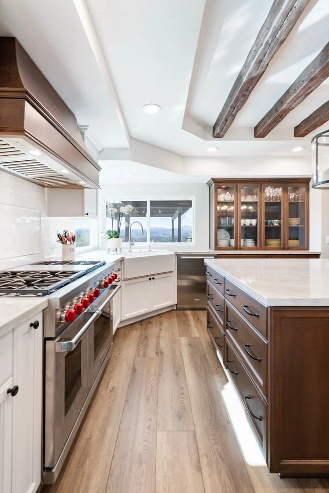 Rancho Peñasquitos, CA kitchen design featuring exposed wood ceiling beams, a professional-grade range, custom cabinetry, and warm traditional finishes by Anne Flynn Designs.