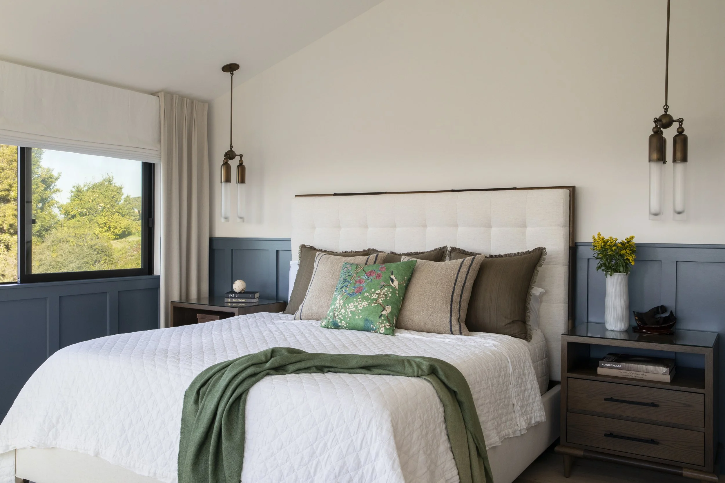 Solana Beach, CA primary bedroom design featuring custom wall paneling, layered bedding, and tailored lighting in a calm, coastal-inspired retreat by Anne Flynn Designs.