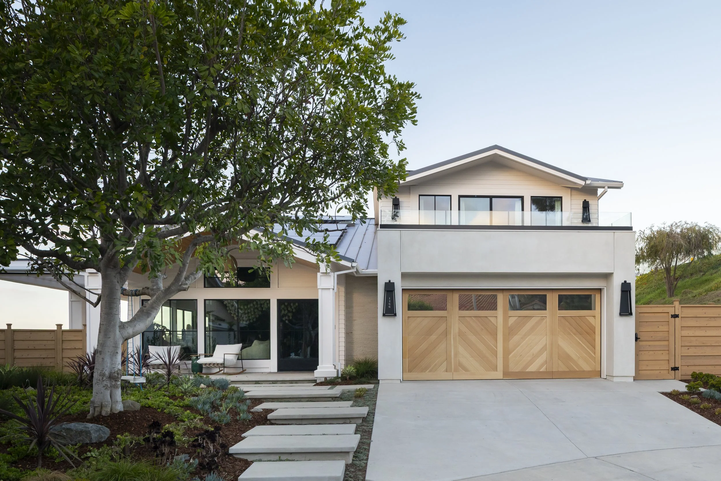 Solana Beach, CA residential exterior design featuring a modern coastal home with clean architectural lines, custom wood garage doors, and integrated landscaping by Anne Flynn Designs, architect SK7 Designs.