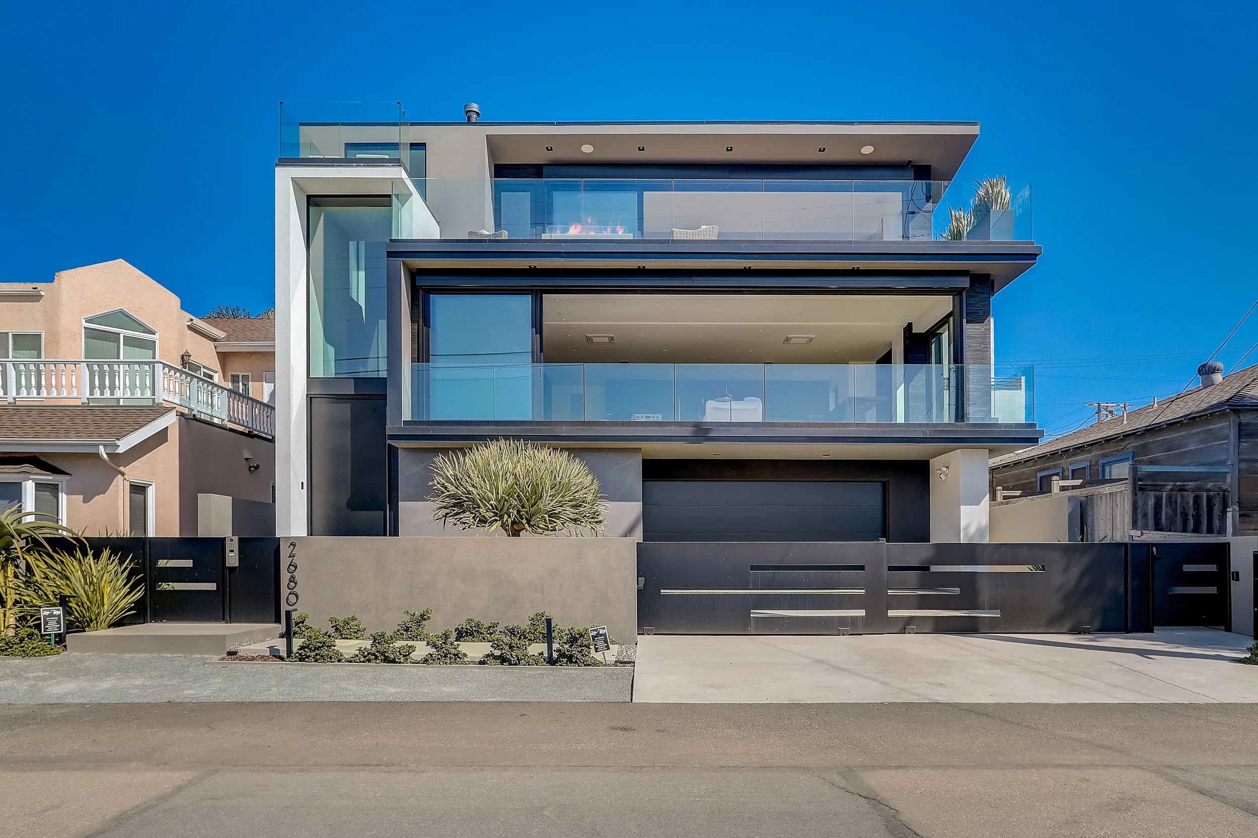 Carlsbad, CA modern beach retreat exterior design featuring a contemporary coastal façade, expansive glass balconies, clean architectural lines, and integrated landscaping by Anne Flynn Designs, architect Samuel Wright.