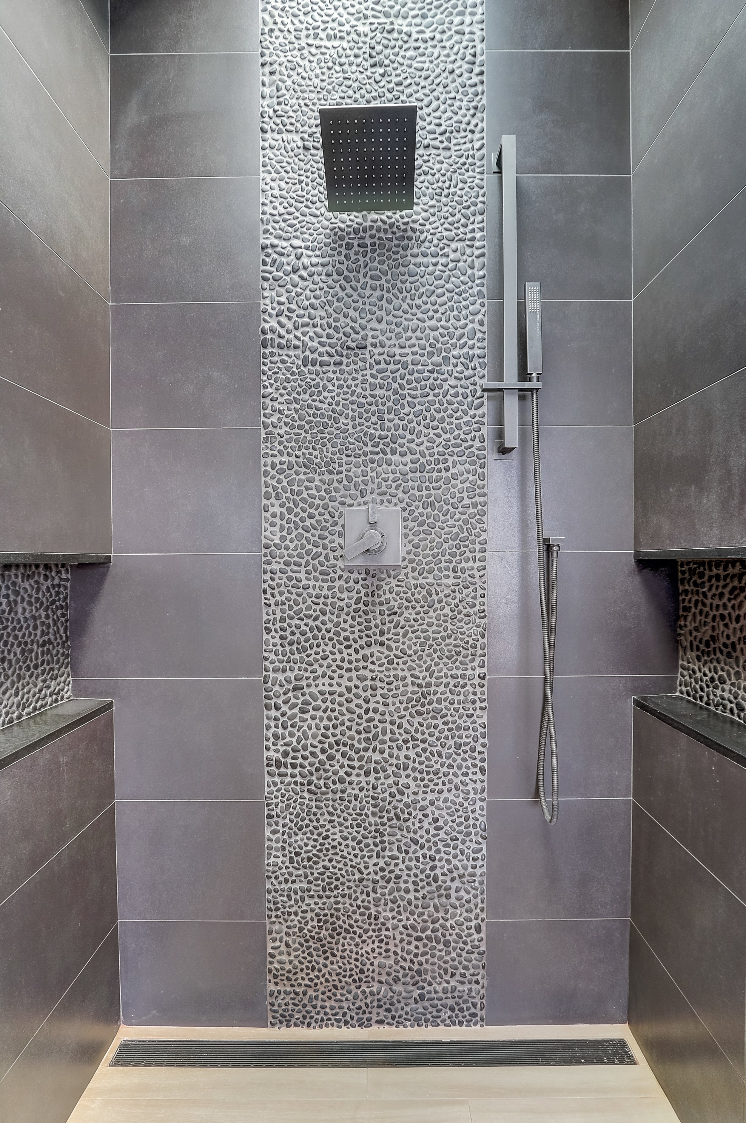 Carlsbad, CA bathroom design featuring a custom walk-in shower with textured stone tile, sleek modern fixtures, and a spa-inspired coastal aesthetic by Anne Flynn Designs.