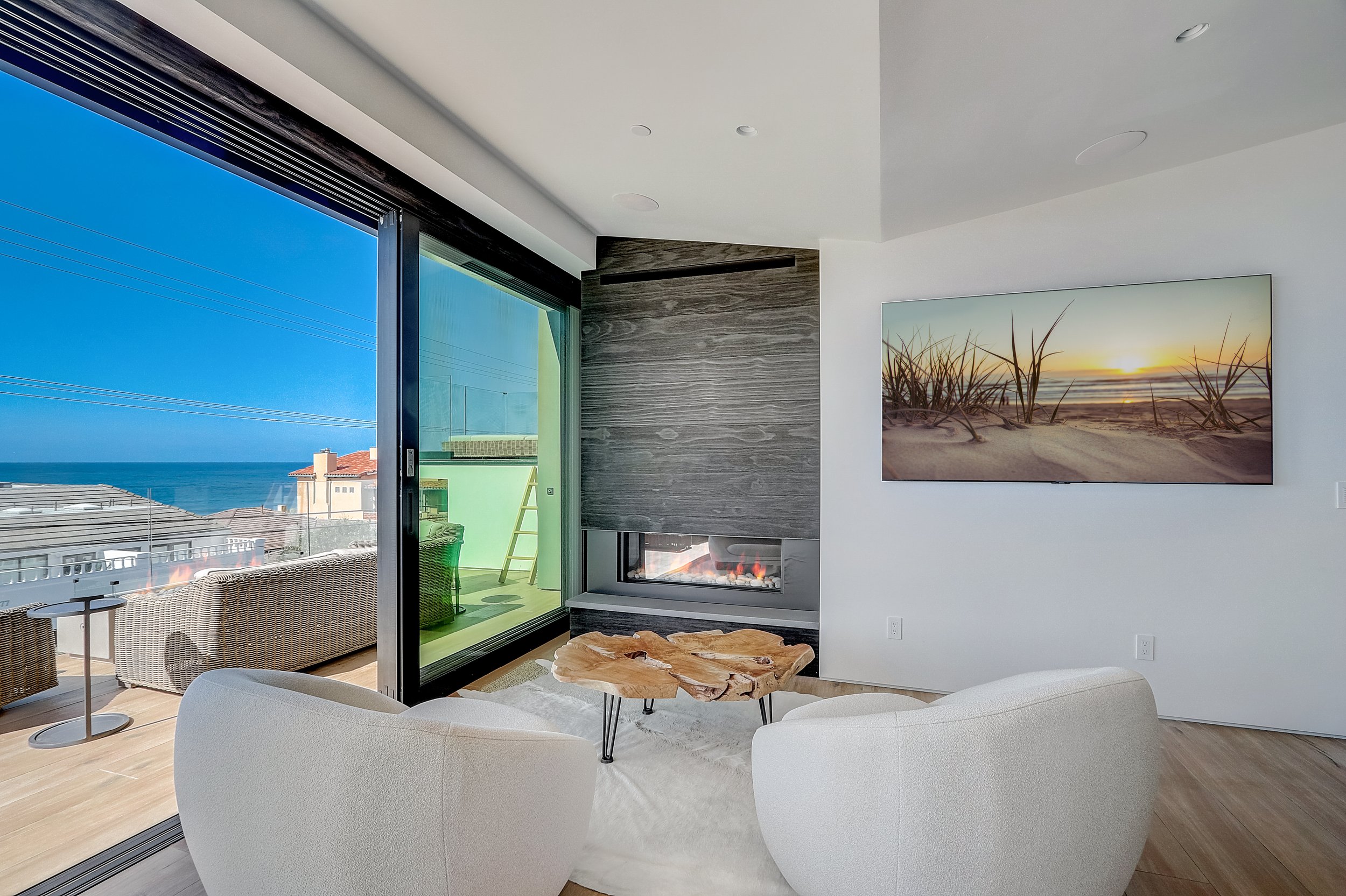 Carlsbad, CA living room design featuring expansive ocean views, a modern fireplace, and clean contemporary furnishings creating a refined coastal retreat by Anne Flynn Designs.