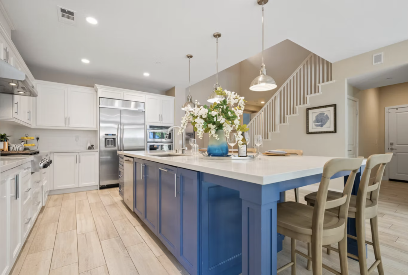 Stone Steps Encinitas, CA kitchen design featuring a bold blue island, classic white cabinetry, quartz countertops, and bright coastal-transitional detailing by Anne Flynn Designs.