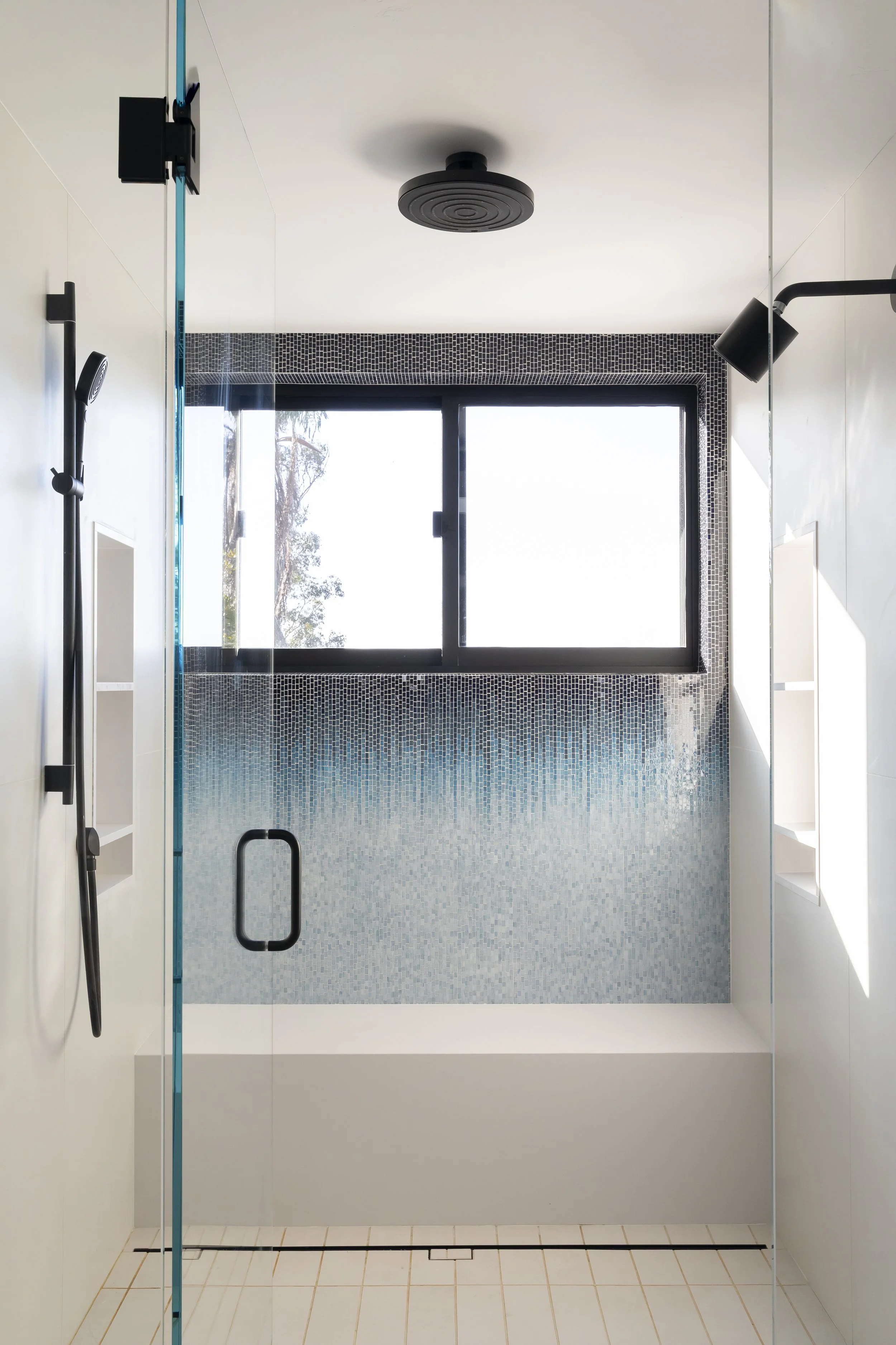 Solana Beach, CA bathroom design featuring a custom walk-in shower with textured blue tile, black fixtures, and clean modern detailing by Anne Flynn.