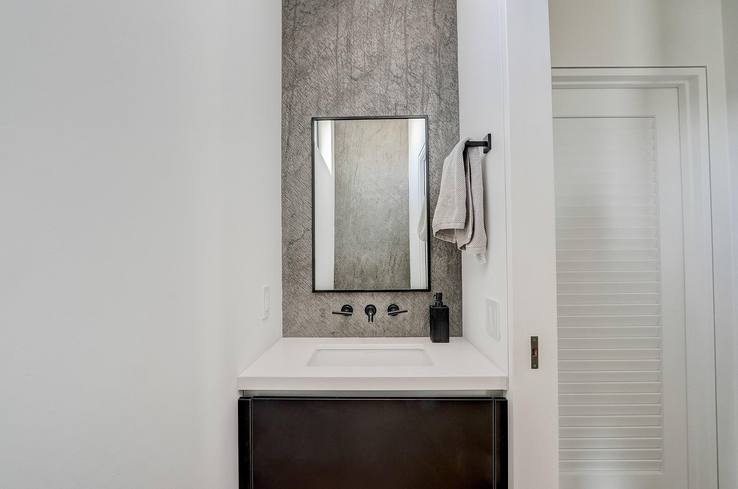 Carlsbad, CA bathroom design featuring a sleek floating vanity, minimalist fixtures, and textured wall finishes for a clean, modern coastal aesthetic by Anne Flynn Designs.