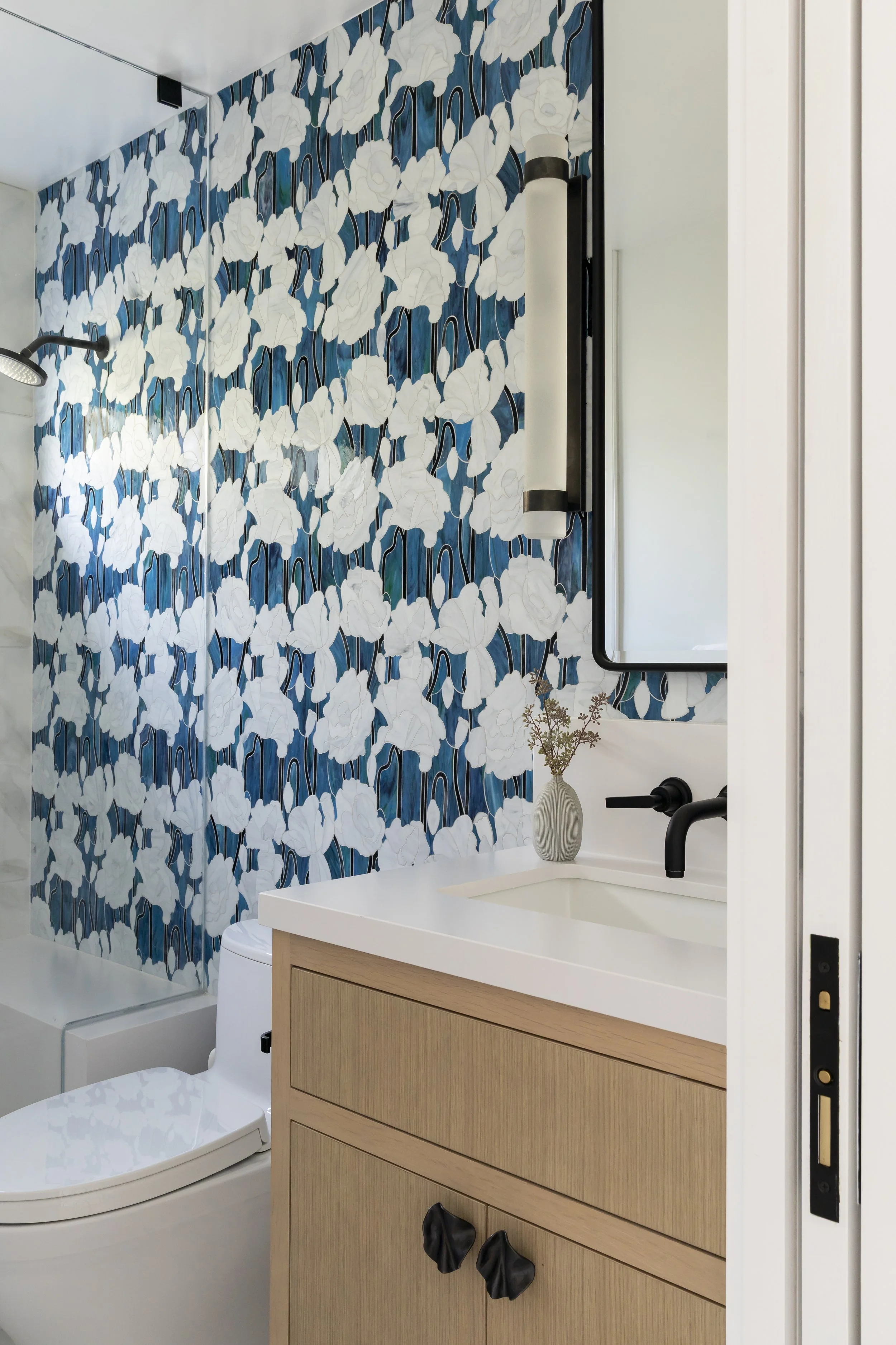 Solana Beach, CA bathroom design featuring a custom wood vanity, floral-patterned tile wall, and refined modern finishes with a coastal influence by Anne Flynn Designs.