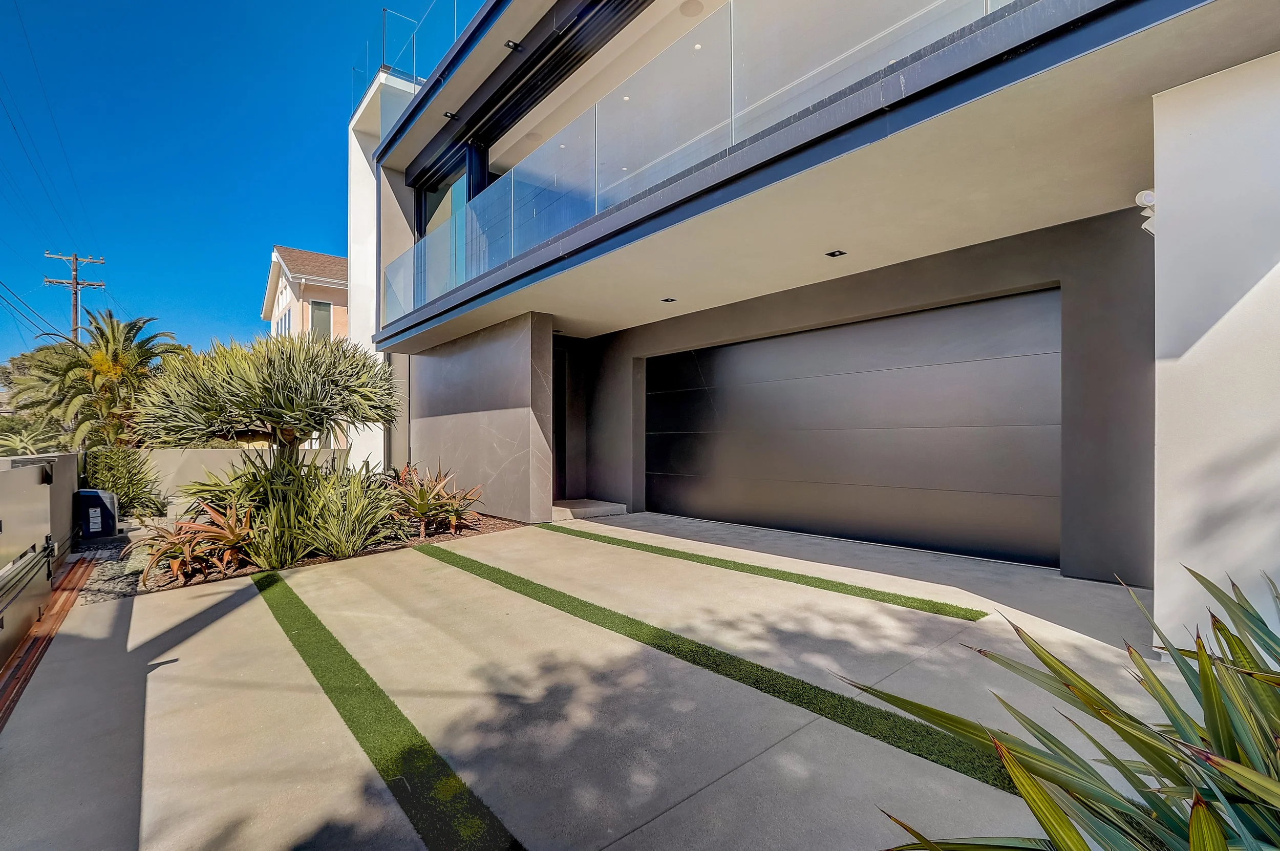 Carlsbad, CA residential exterior design featuring a modern coastal façade, clean architectural lines, integrated landscaping, and a sleek garage approach by Anne Flynn Designs, built by WNC Contractors.