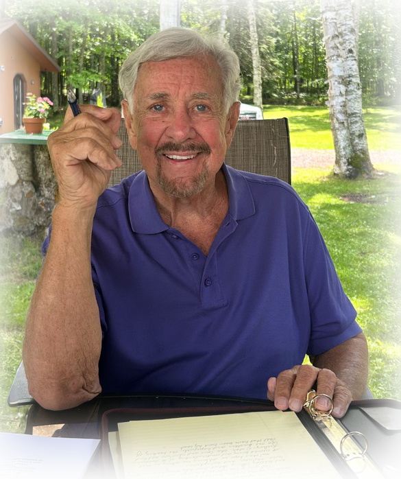 Author John David Hanna smiles while writing at an outdoor table