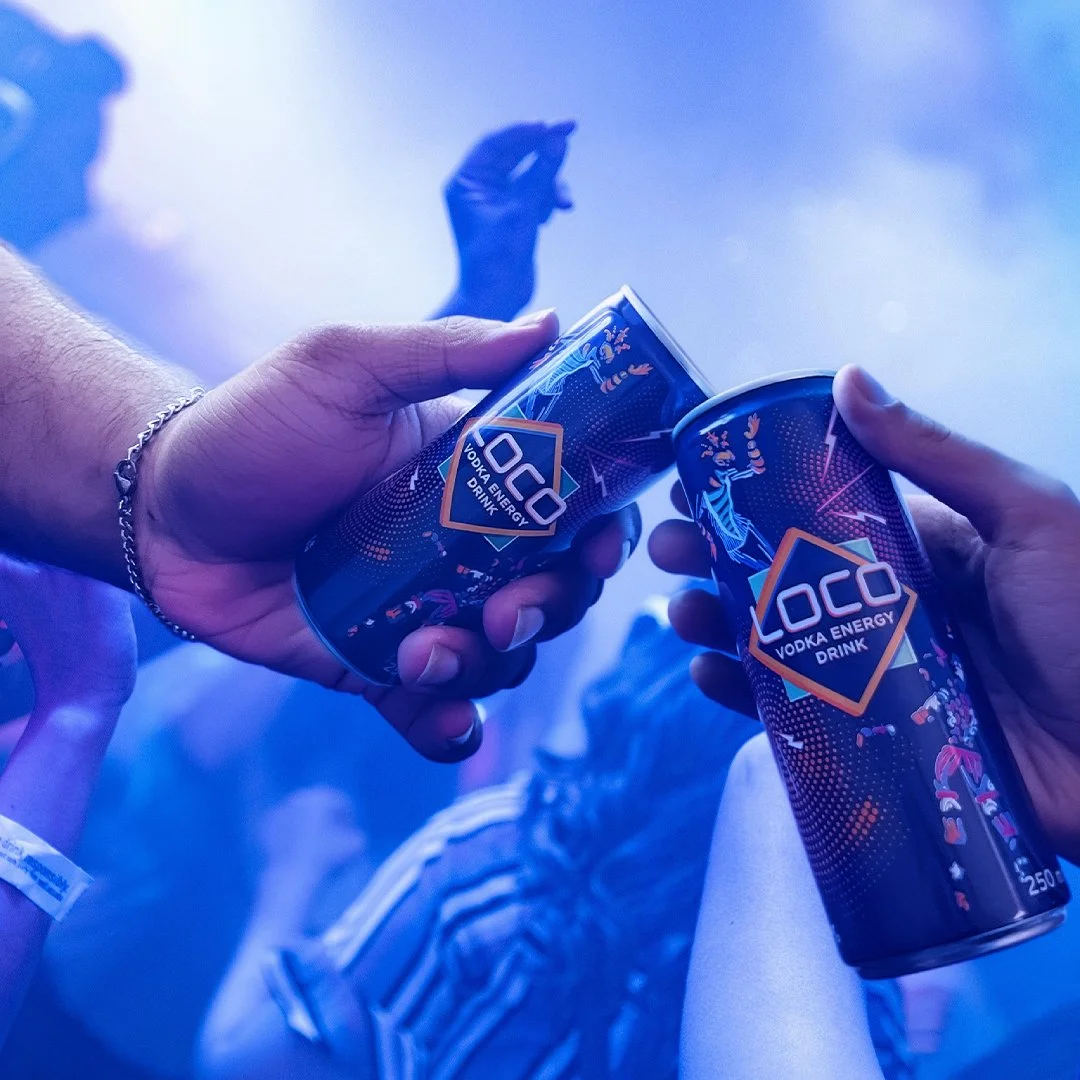 Deux personnes qui tiennent des canettes de boisson énergétique Loco devant un fond de lumière bleue.