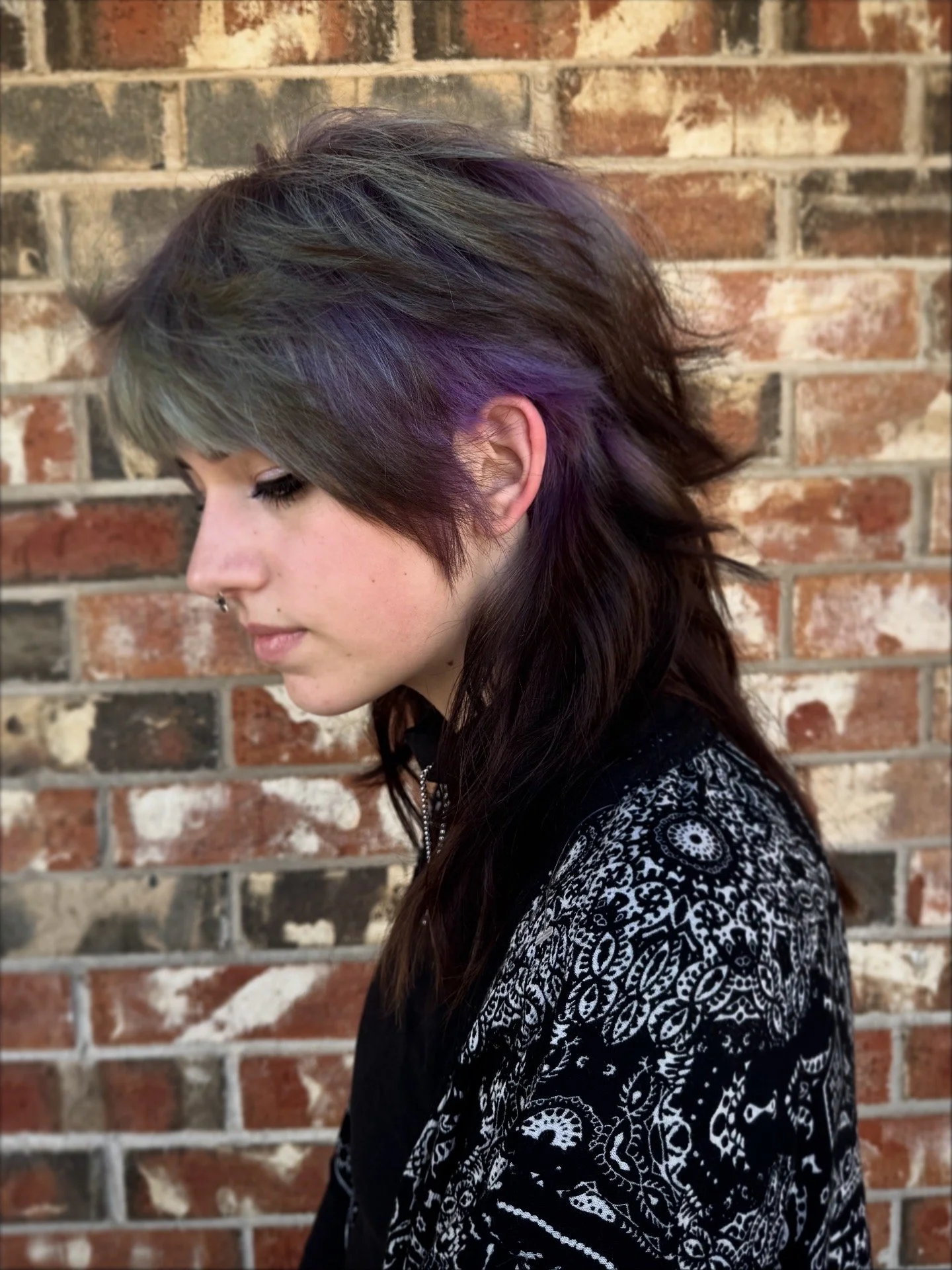 person with a long textured mullet haircut with faded blue and purple ghost roots