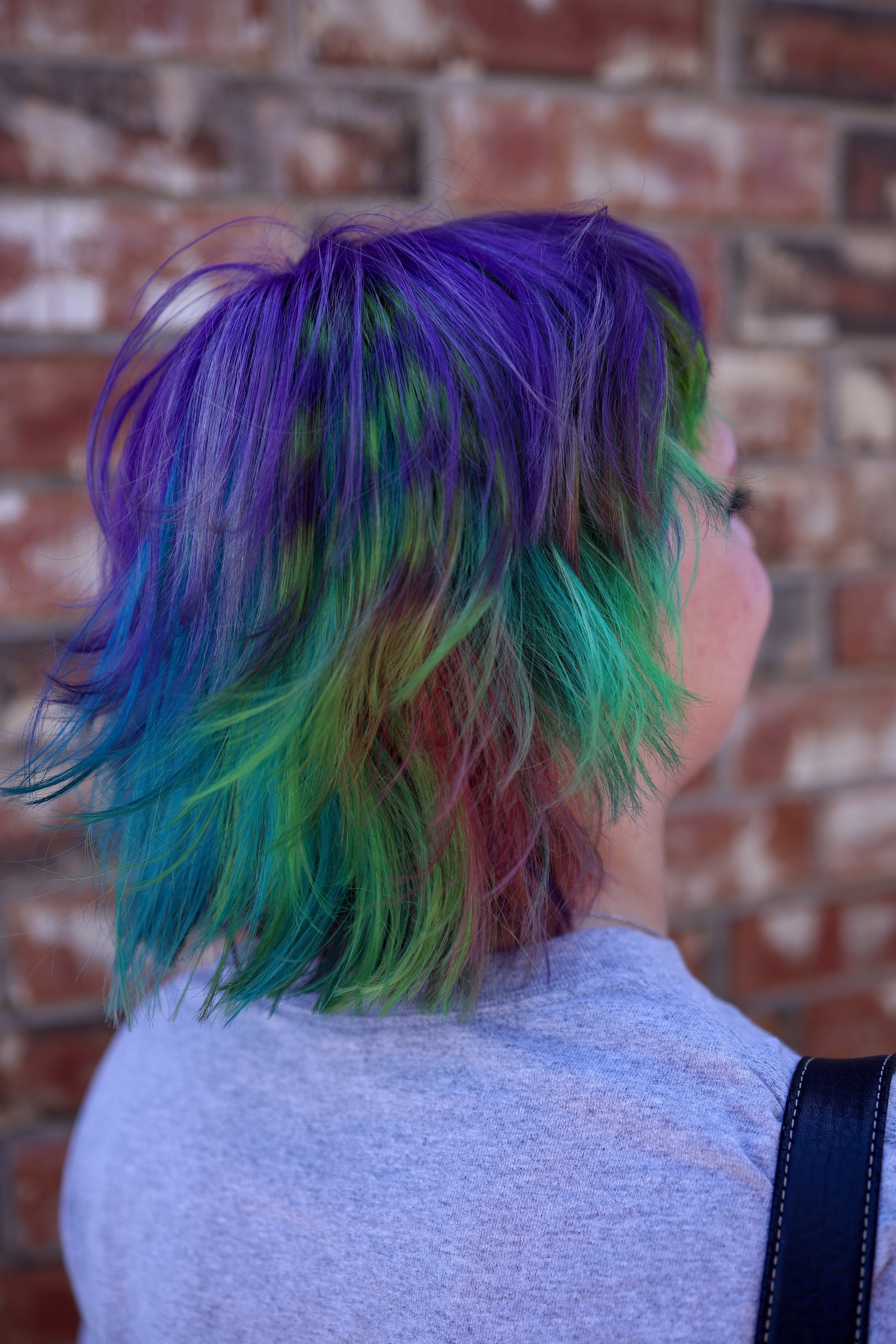 girl with short multi-colored hair. purple, teal, bright green, pink, and blue with a green and purple raccoon stripe