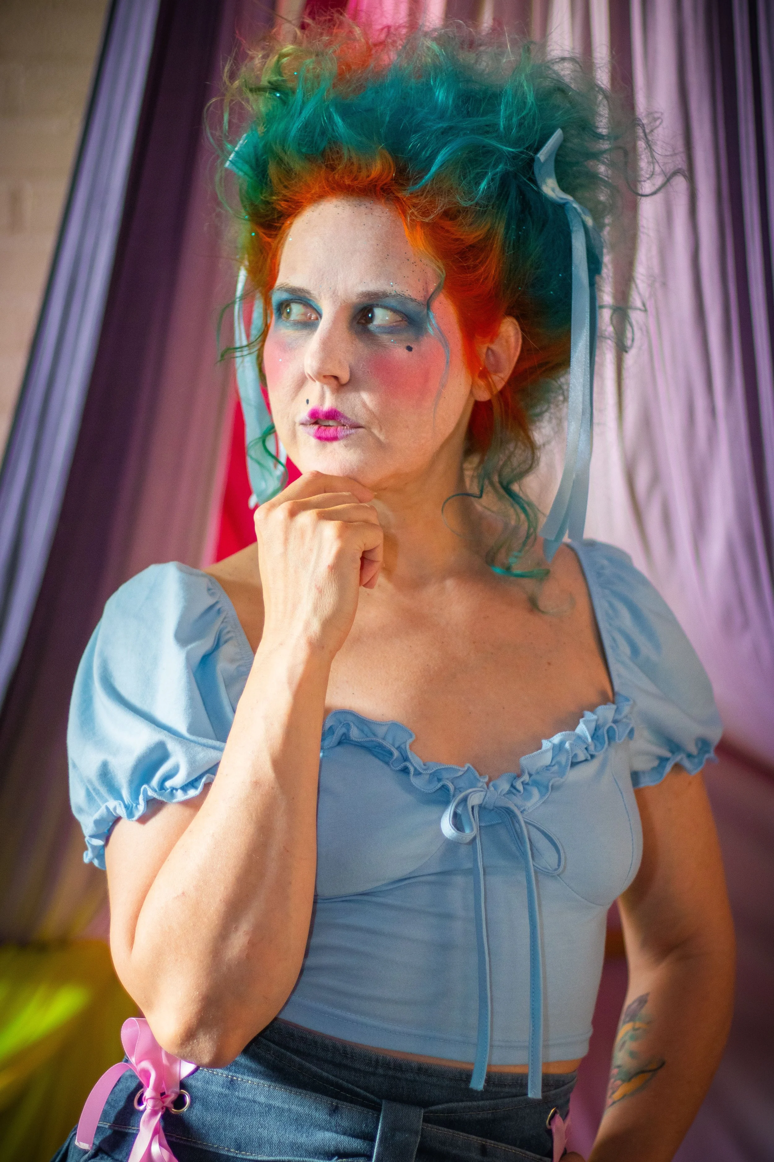 vibrant portrait of a model with coquette or Marie Antoinette inspired hair. Outfit and hair inspired by Hades from Hercules