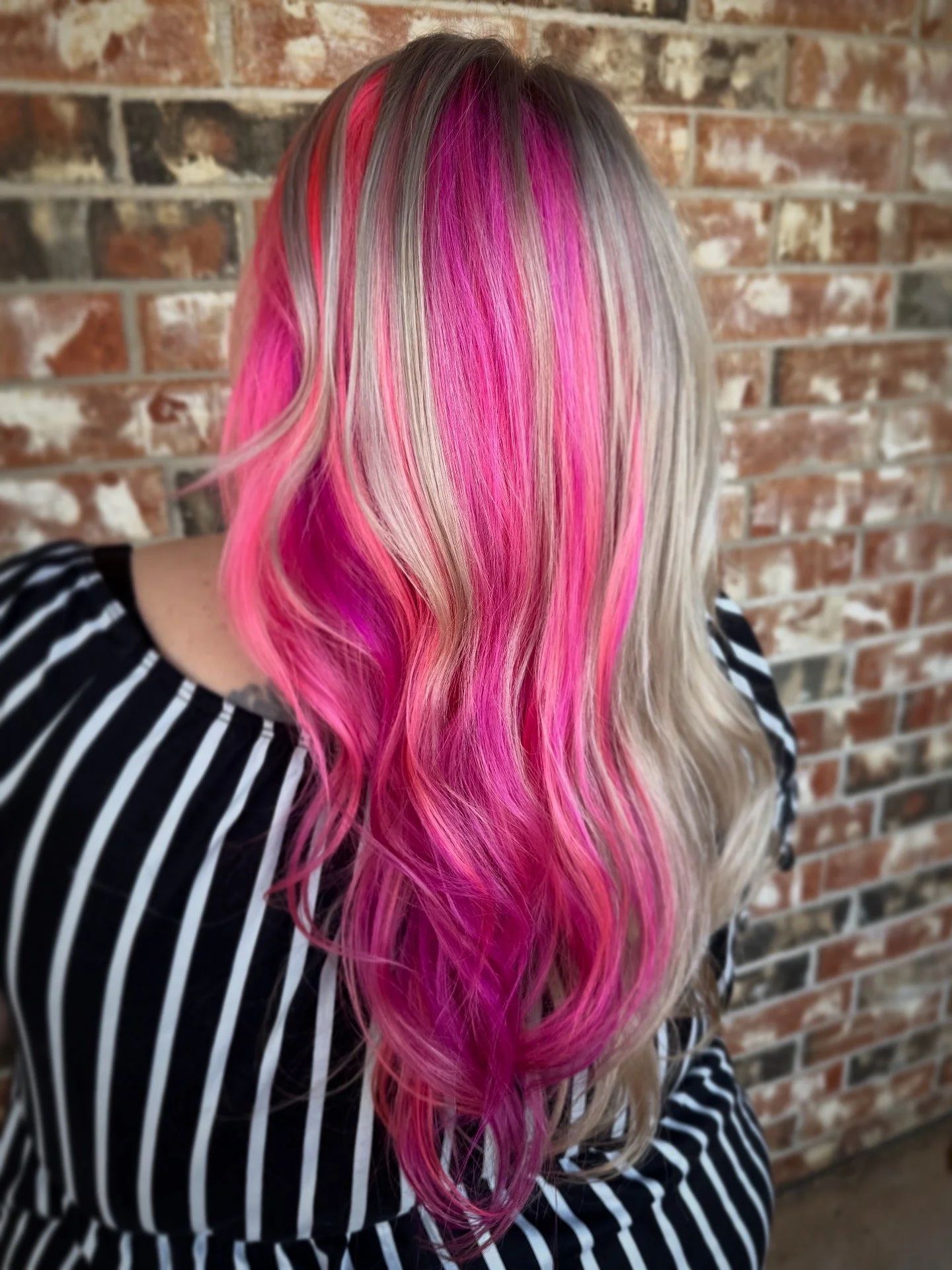 woman with medium length blonde hair with different shades of pink color block sections throughout