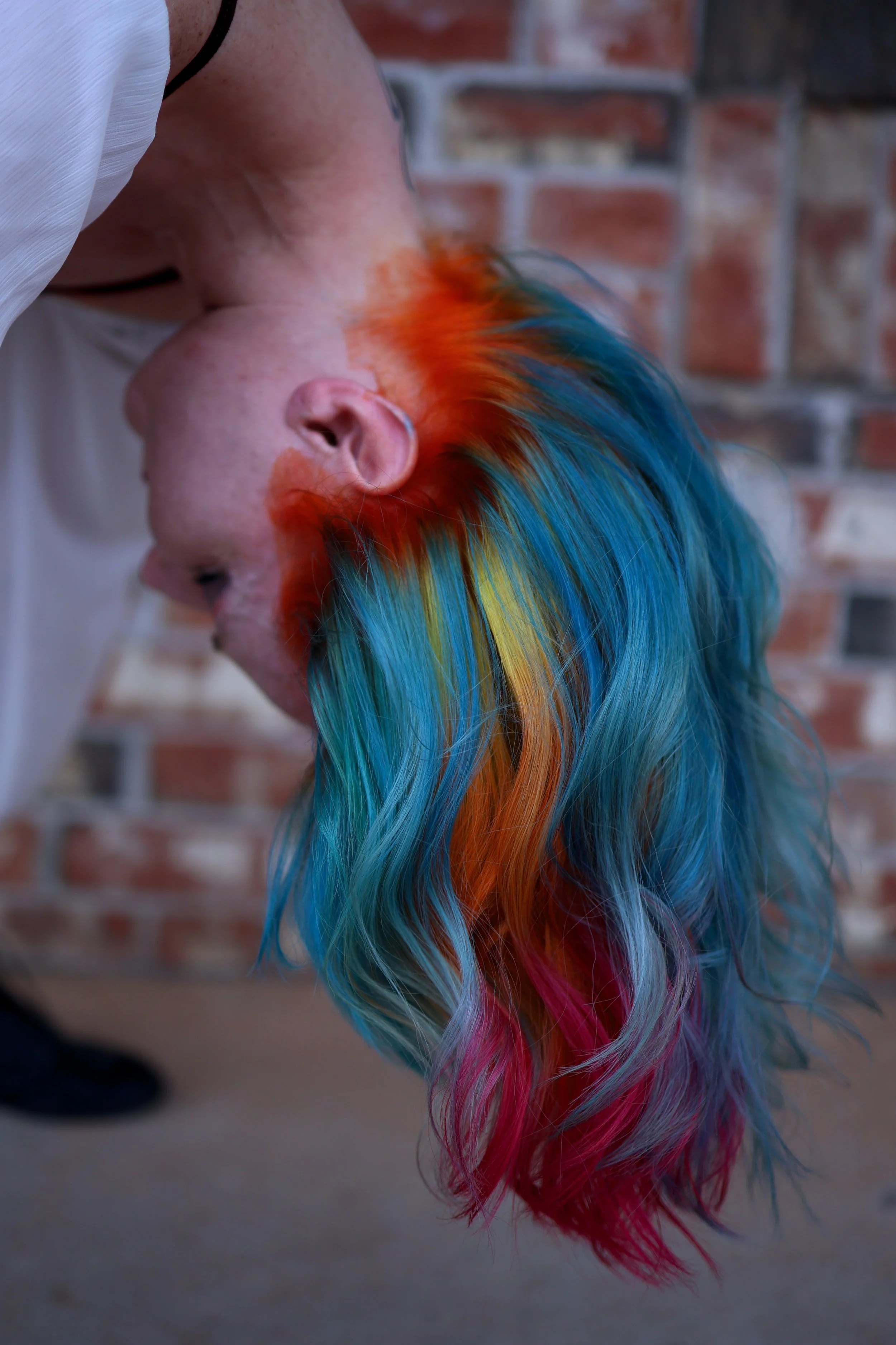 woman with her head turned upside down to emphasize her blue hair with orange ghost roots and a red orange and yellow color melt resembling fire. inspired by Hades from Hercules