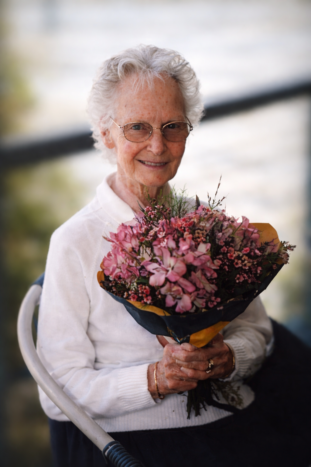 Portrait of Olive Mabel Joyce holding a bouquet of pink flowers, seated outdoors, smiling gently at the camera.