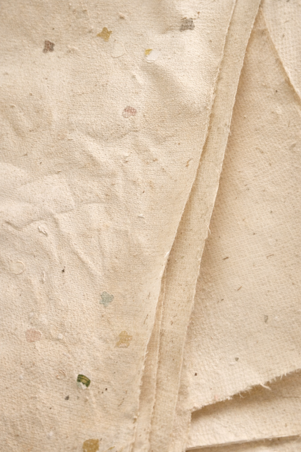 Close-up texture of handmade recycled paper with visible fibres and subtle natural tones.