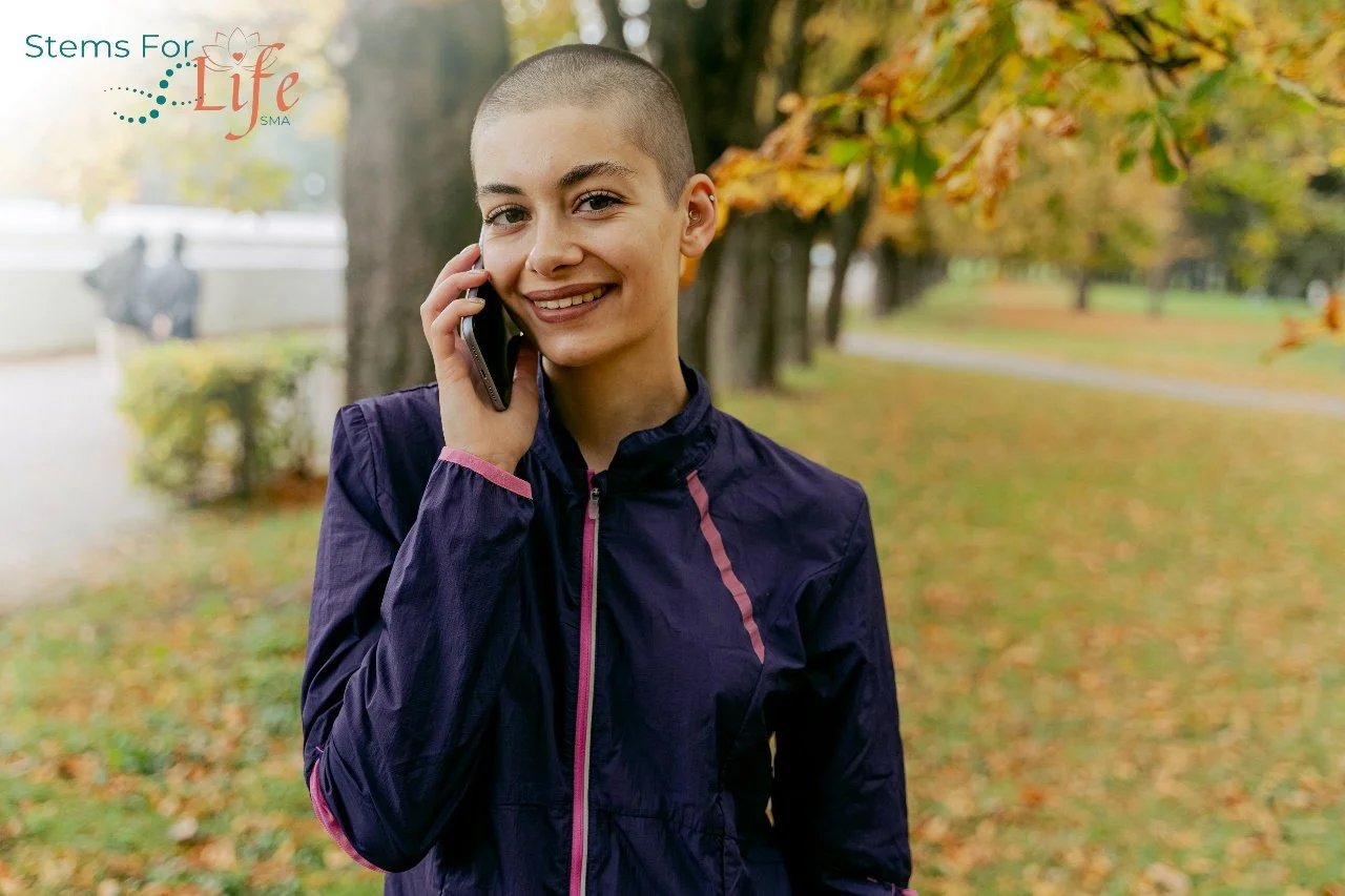 Woman cancer patient smiling outdoors in a park, symbolizing hope and healing through advanced cell therapy
