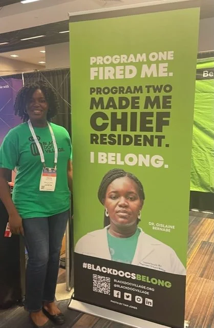 A woman standing next to a green banner that reads: 'Program One Fired Me. Program Two Made Me Chief Resident. I Belong.' The banner features a photo of Dr. Gislain Bernabe and hashtags #BLACKDOCSBELONG, along with social media icons and a QR code.