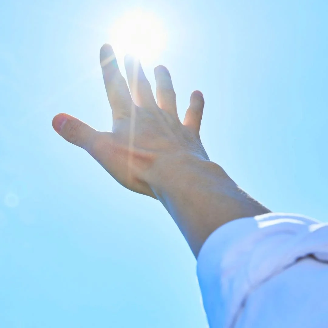 Hand reaching upward toward light and sky