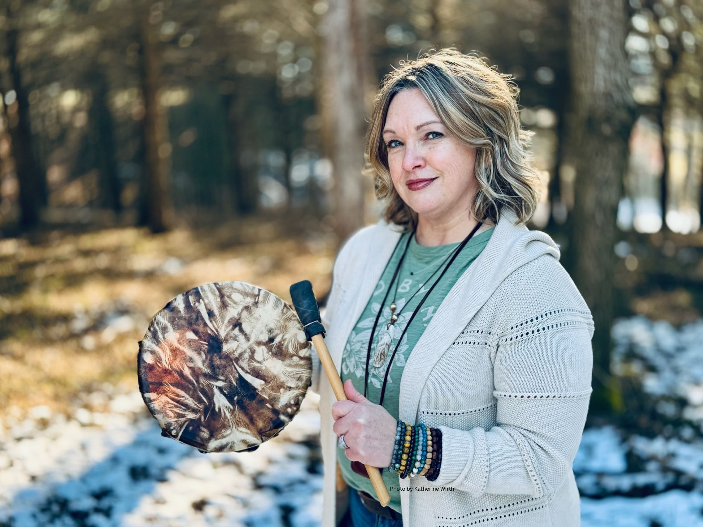 Heidi Doser in the forest tapping a drum