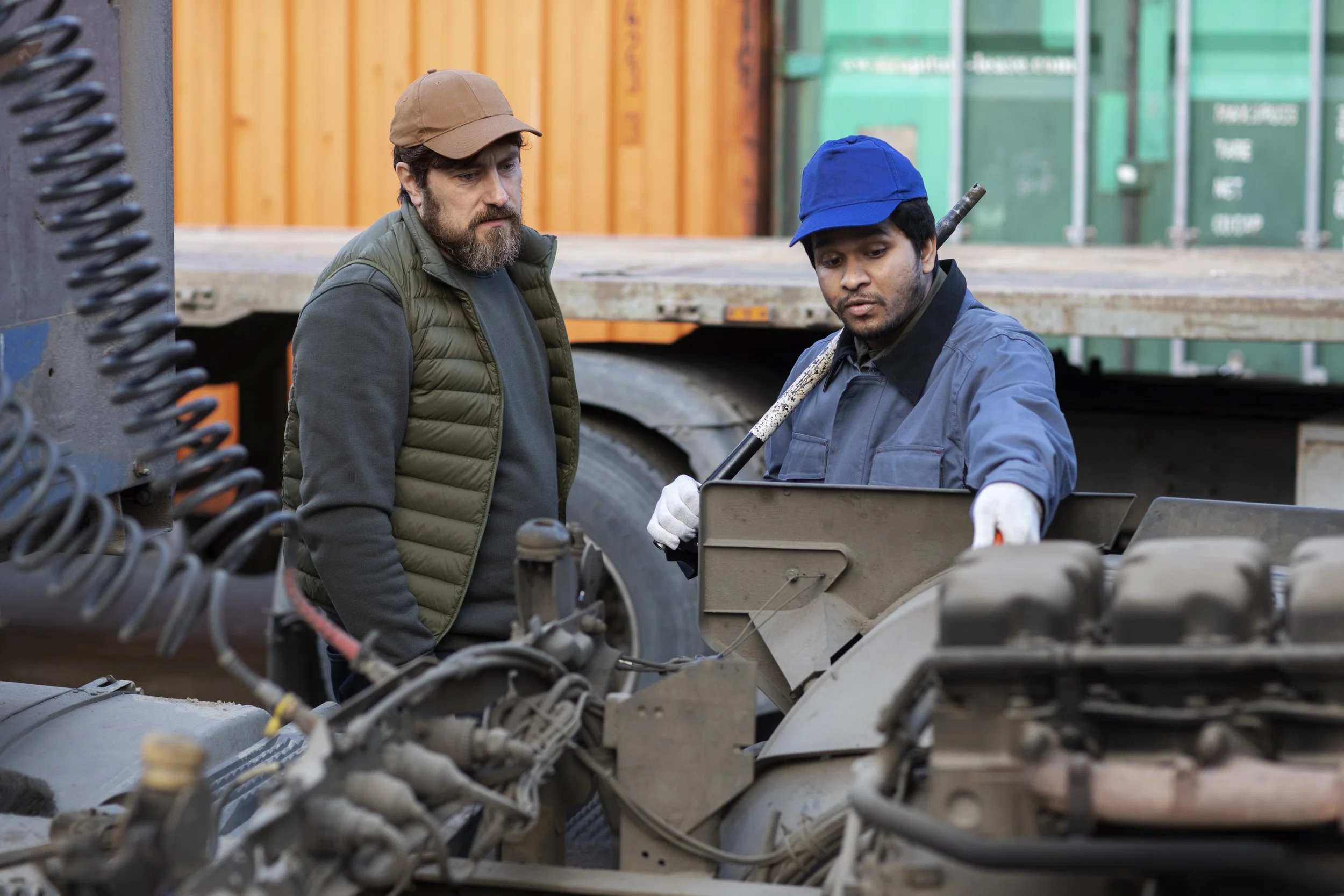 Two men working on a large industrial machine at a construction site or industrial facility.
