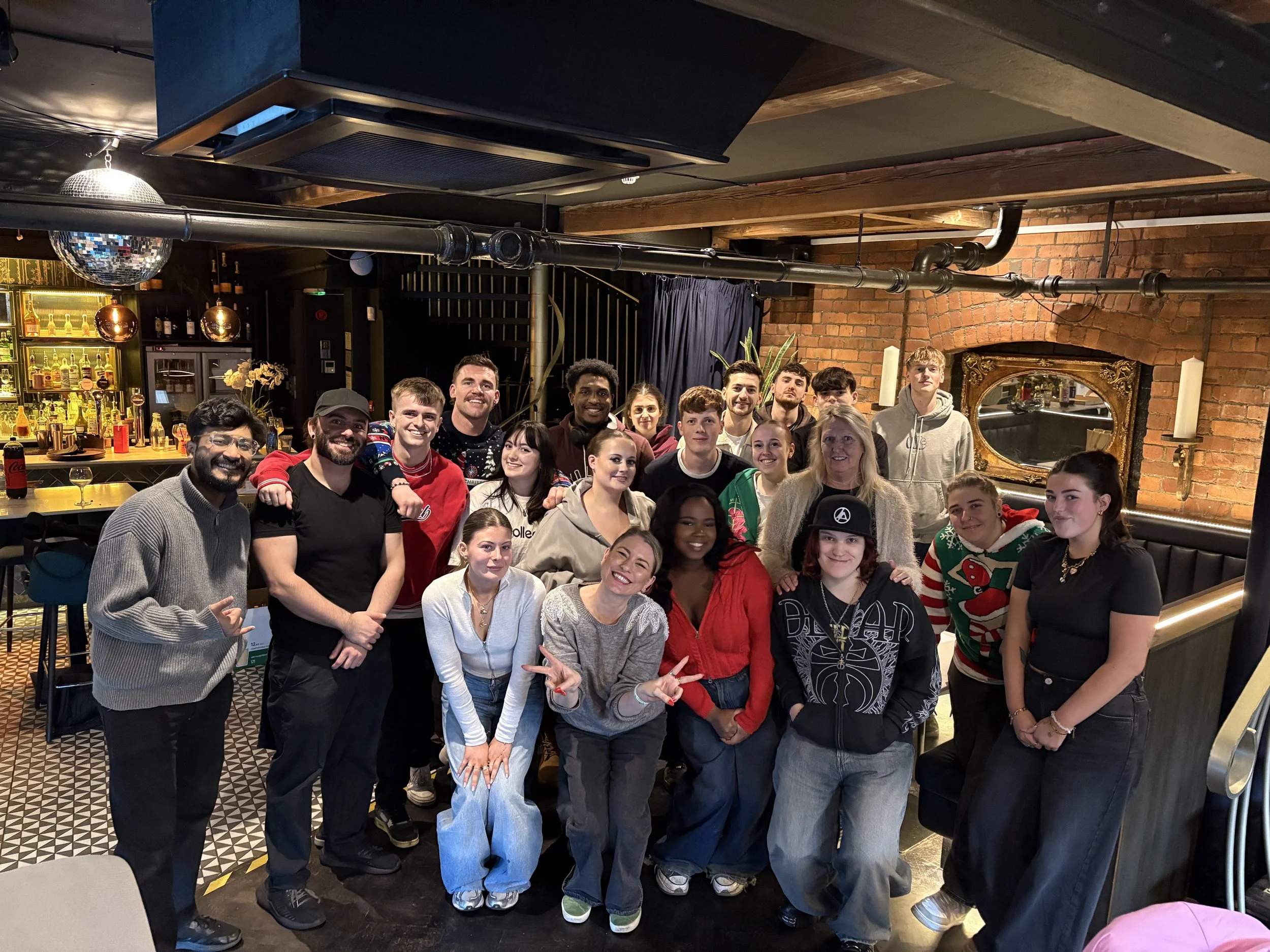 Group of people gathered together in a restaurant or bar, smiling at the camera.