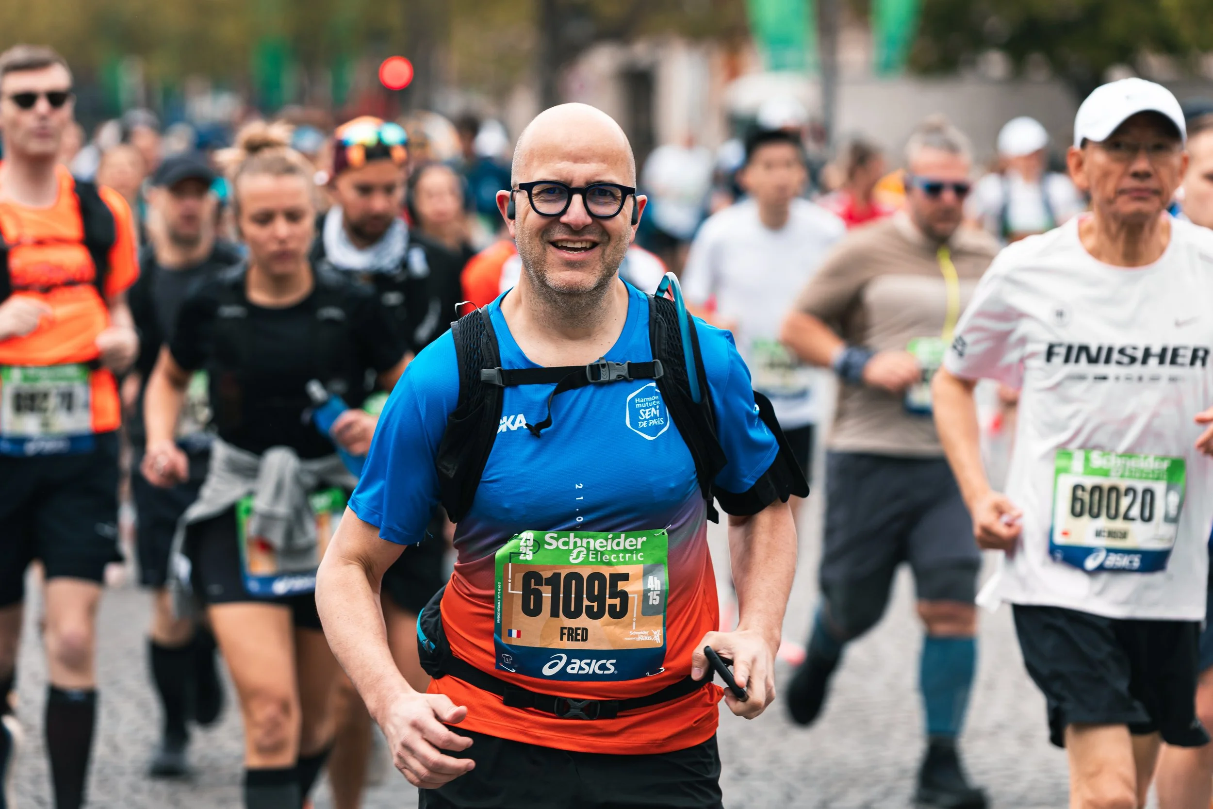 Groupe de coureurs participant à un marathon, portant des dossards et des vêtements de sport, dans une ville.