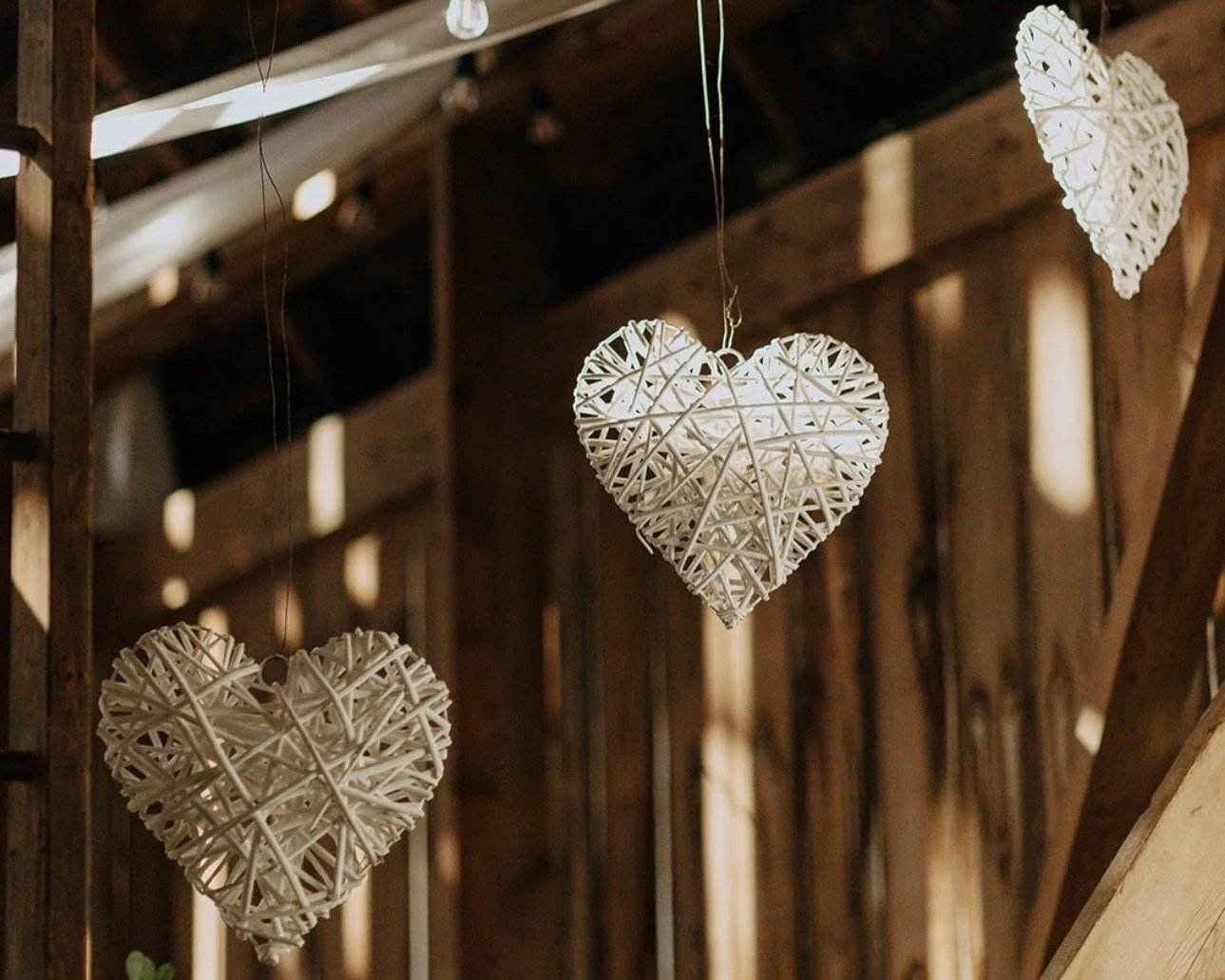 Hanging white wicker hearts in a rustic wooden interior.