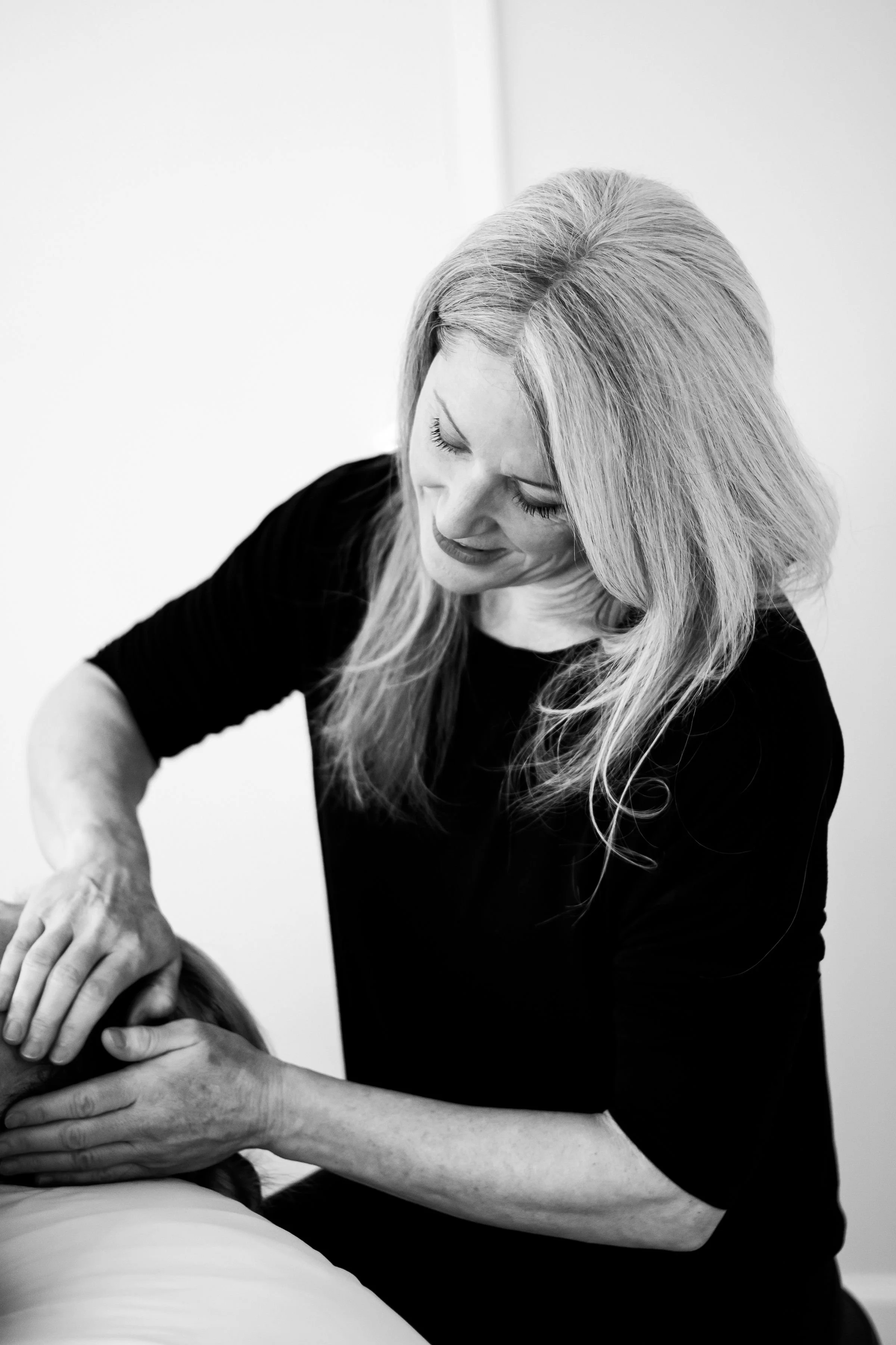 Black and white image of a woman providing massage therapy for a client.
