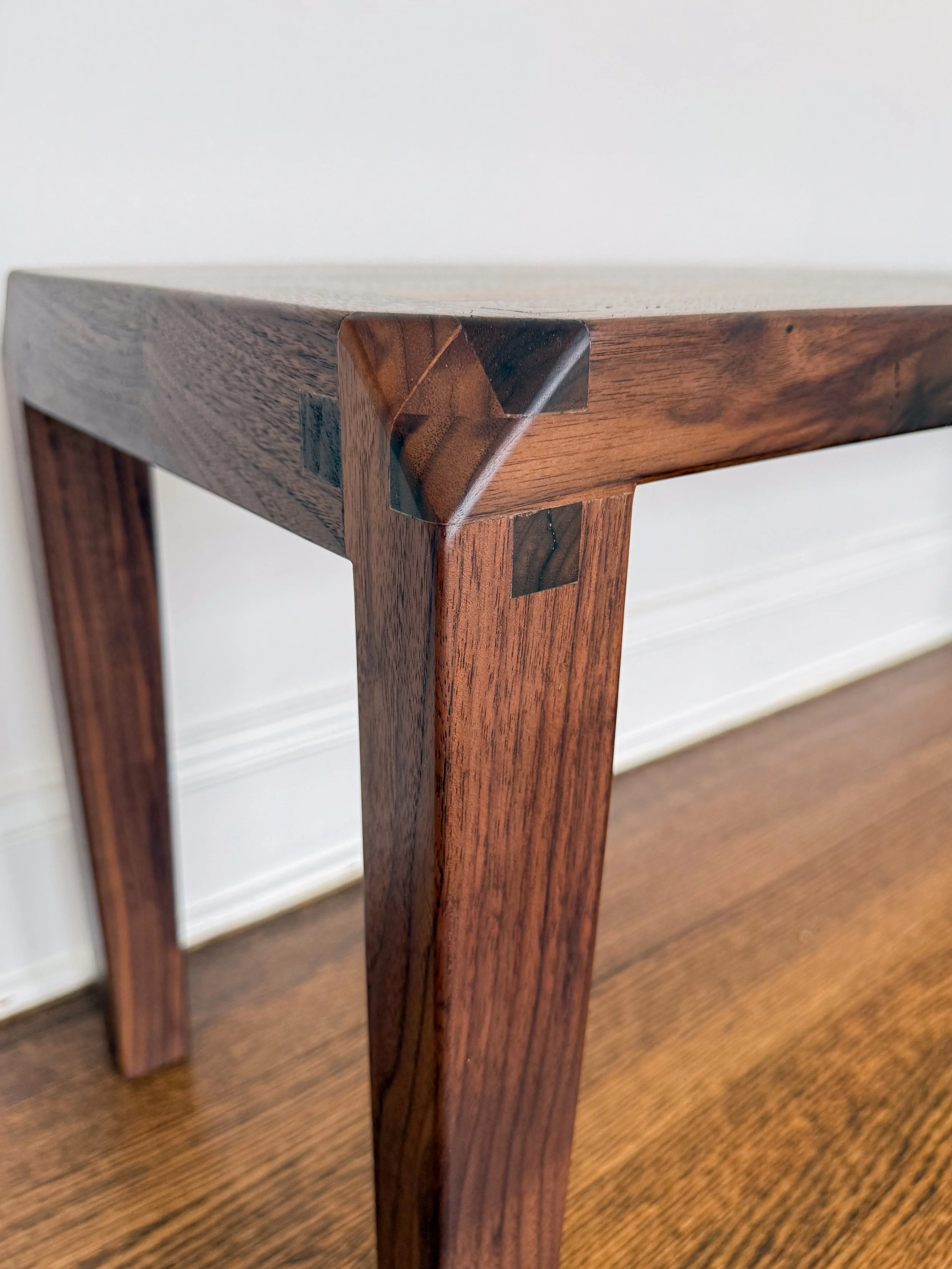 Close-up of a wooden table corner with a dovetail joint showing intricate wood joinery detail.