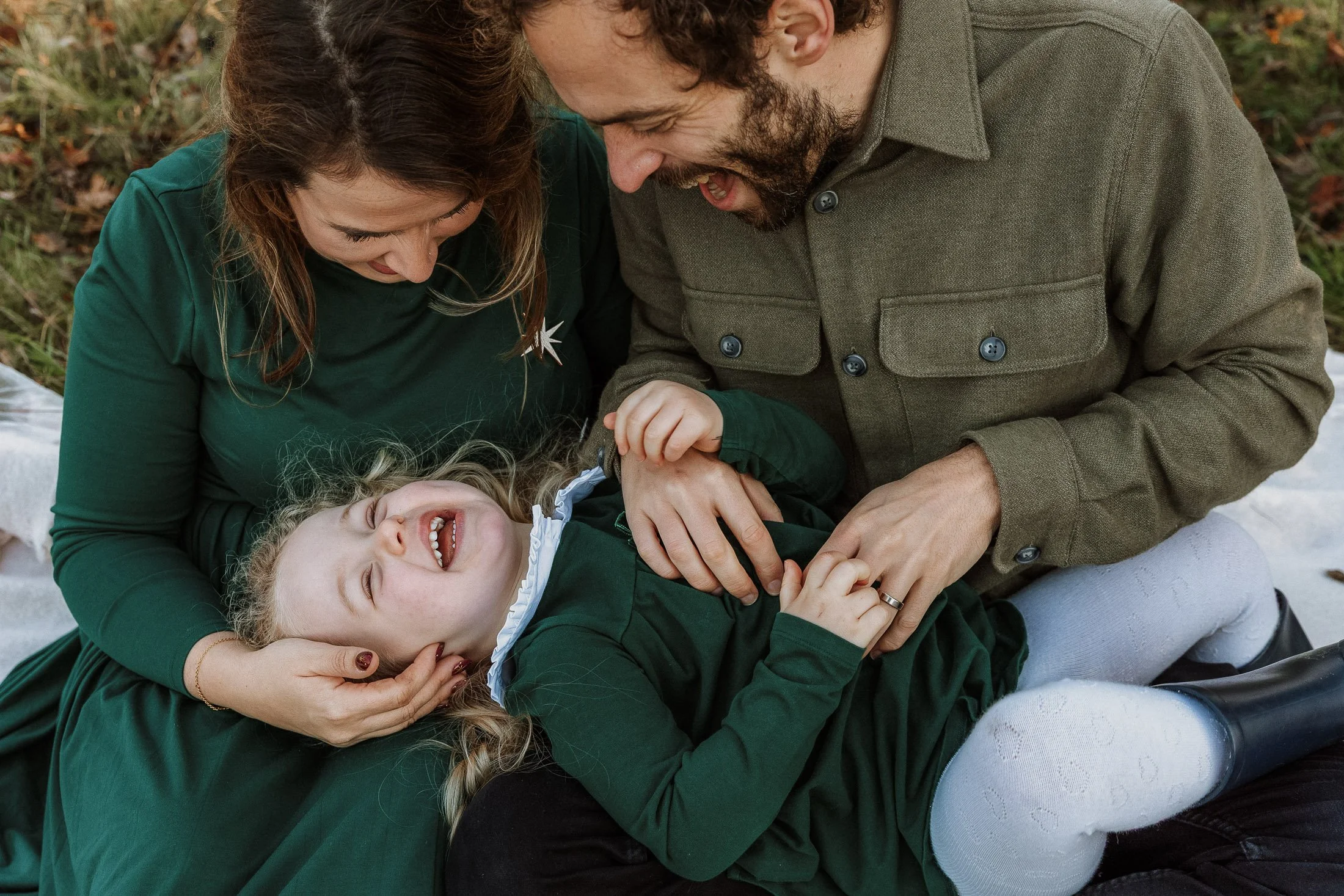 Family photo with two parents and little girl on outdoor shoot in Surrey park in autumn