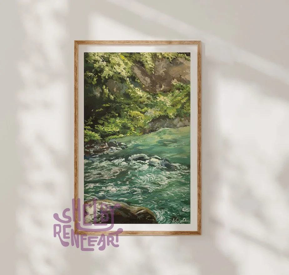 Framed landscape painting of a river flowing through a forest with green foliage and rocks.