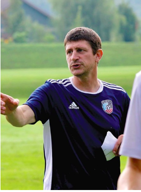 A picture of Chris George a middle aged white man in a blue shirt pointing