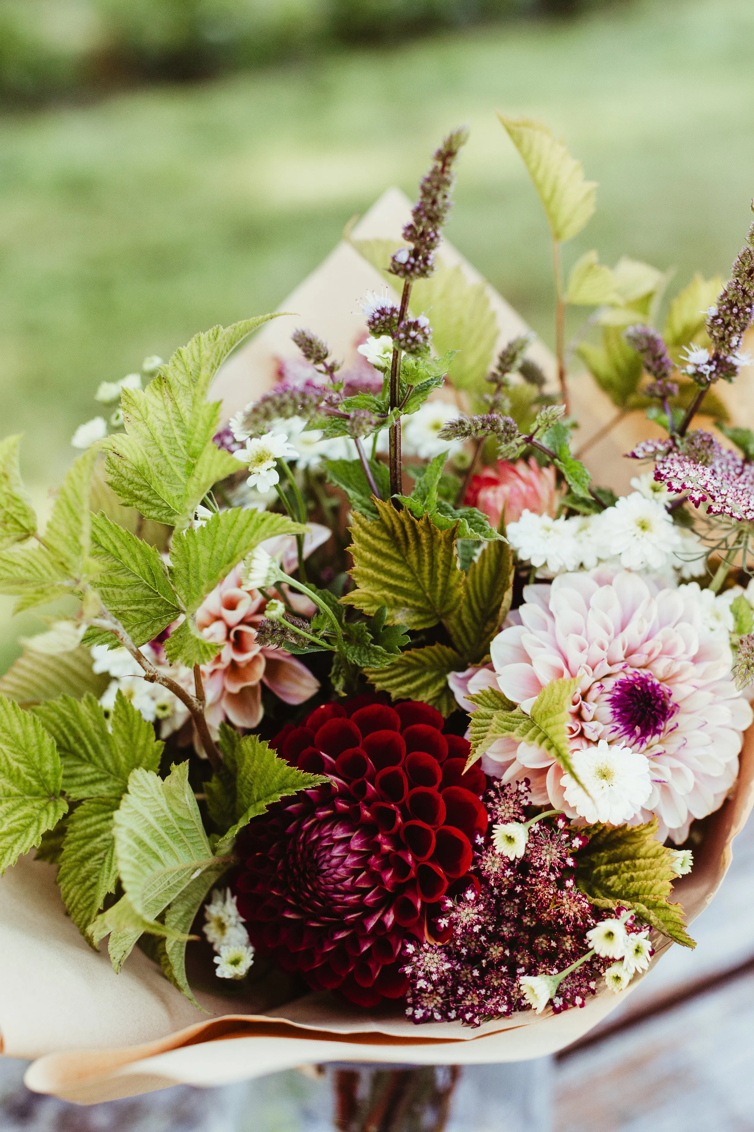 Bouquet of assorted flowers, including dahlias, small white flowers, purple lavender, and green foliage.