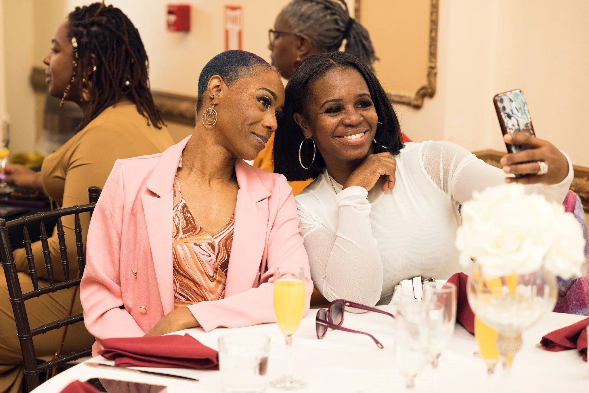 Two women sitting at a table taking a selfie together.