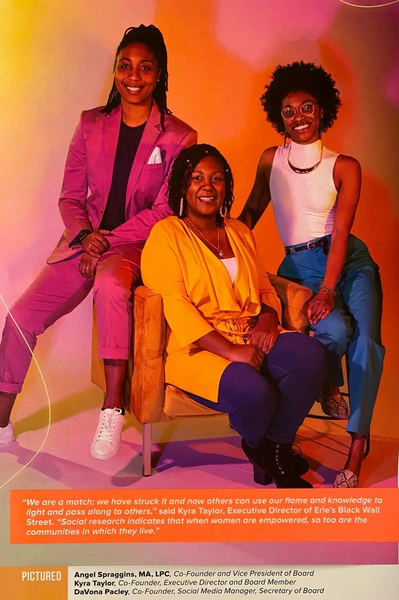 Three women smiling, all seated at various levels on one chair and stool.