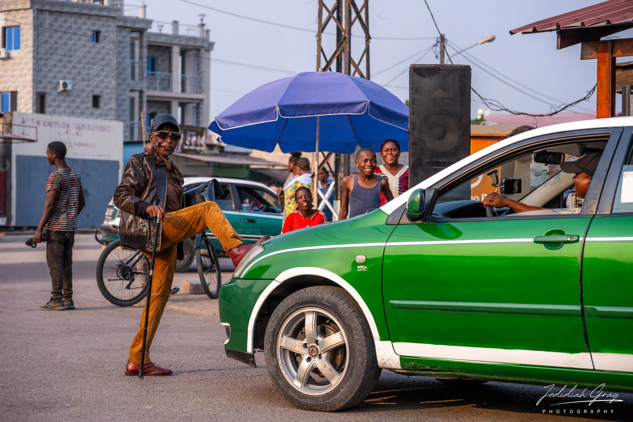 A Congolese sapeur stops a taxi for a pose during a performance in Brazzaville 