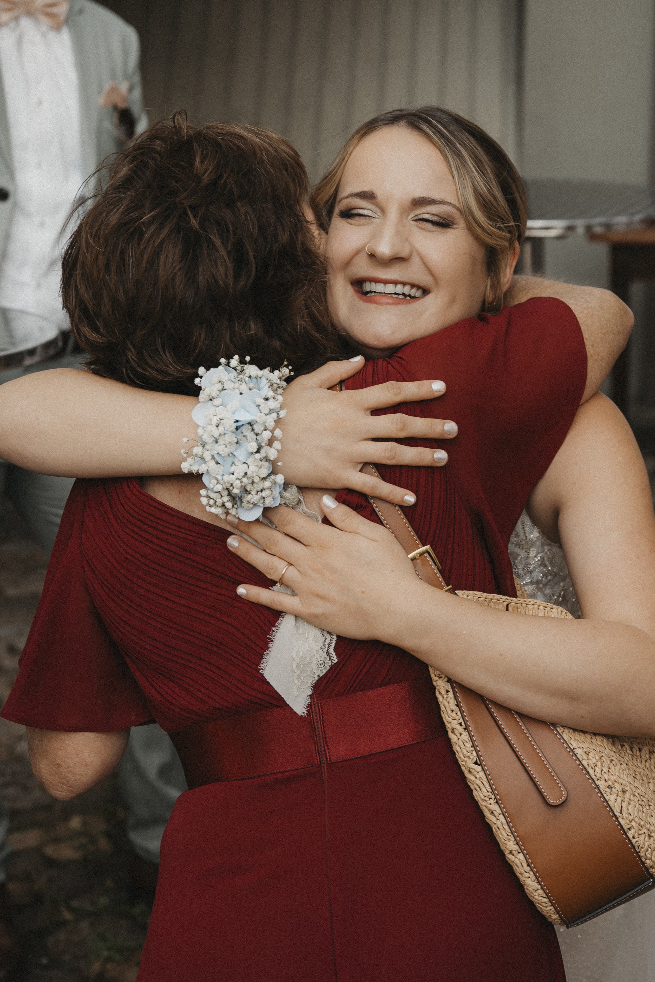 Zwei Frauen umarmen sich herzlich, eine lächelt glücklich.