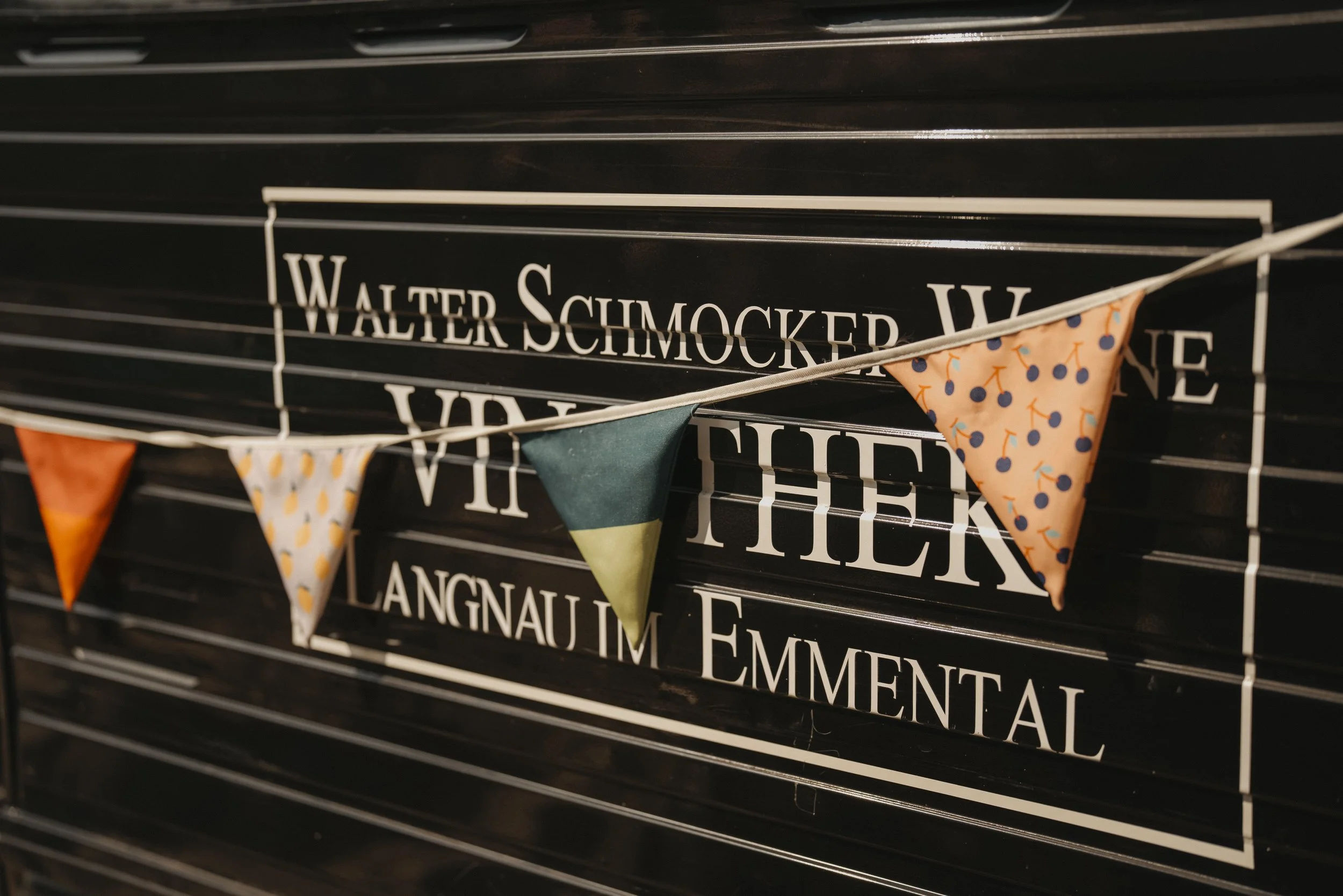 Dekorative bunte Wimpel vor schwarzer Lampe mit weißen Buchstaben