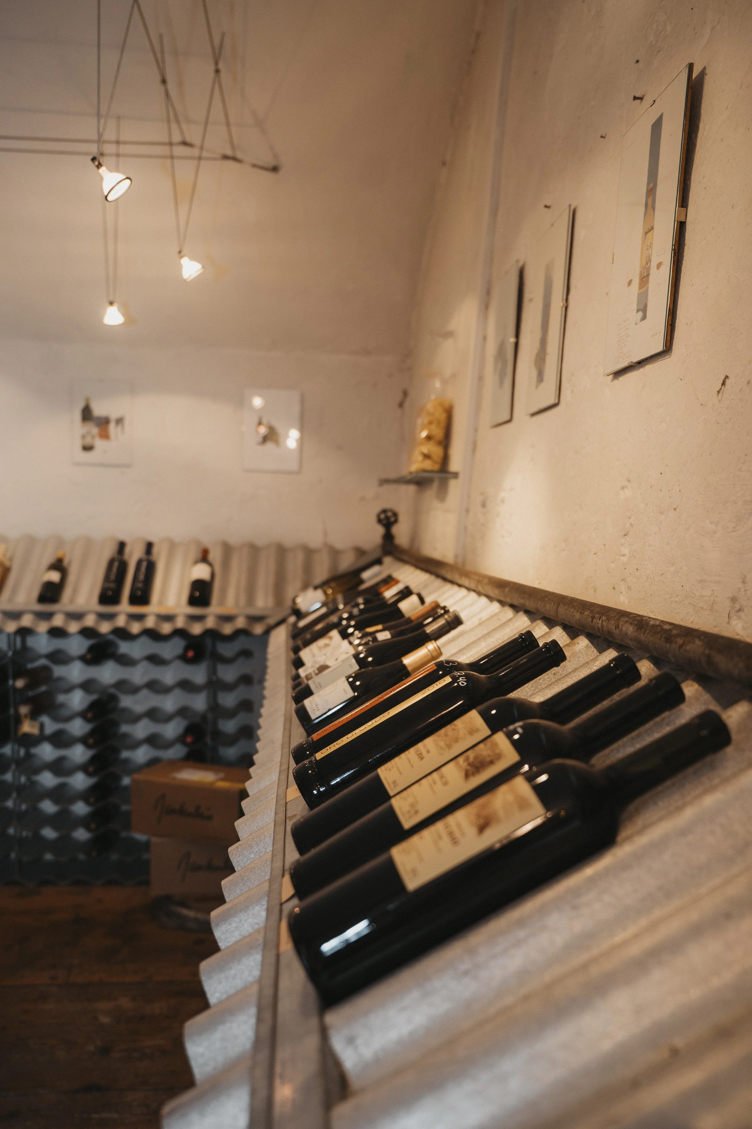 Weinflaschen in einer Weinhandlung, Blick auf die Flaschen auf dem Weinregal und an der Wand, gemütliche Atmosphäre.