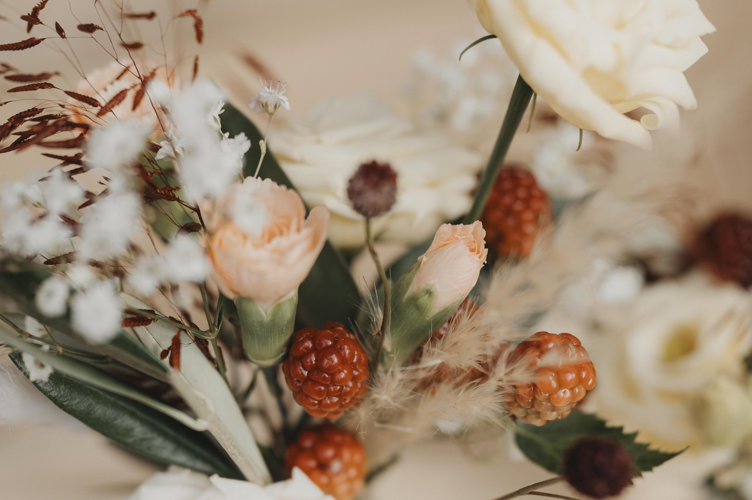 Nahaufnahme eines Blumenstraußes mit weißen, rosa und roten Blumen, getrockneten Gräsern und Blättern.