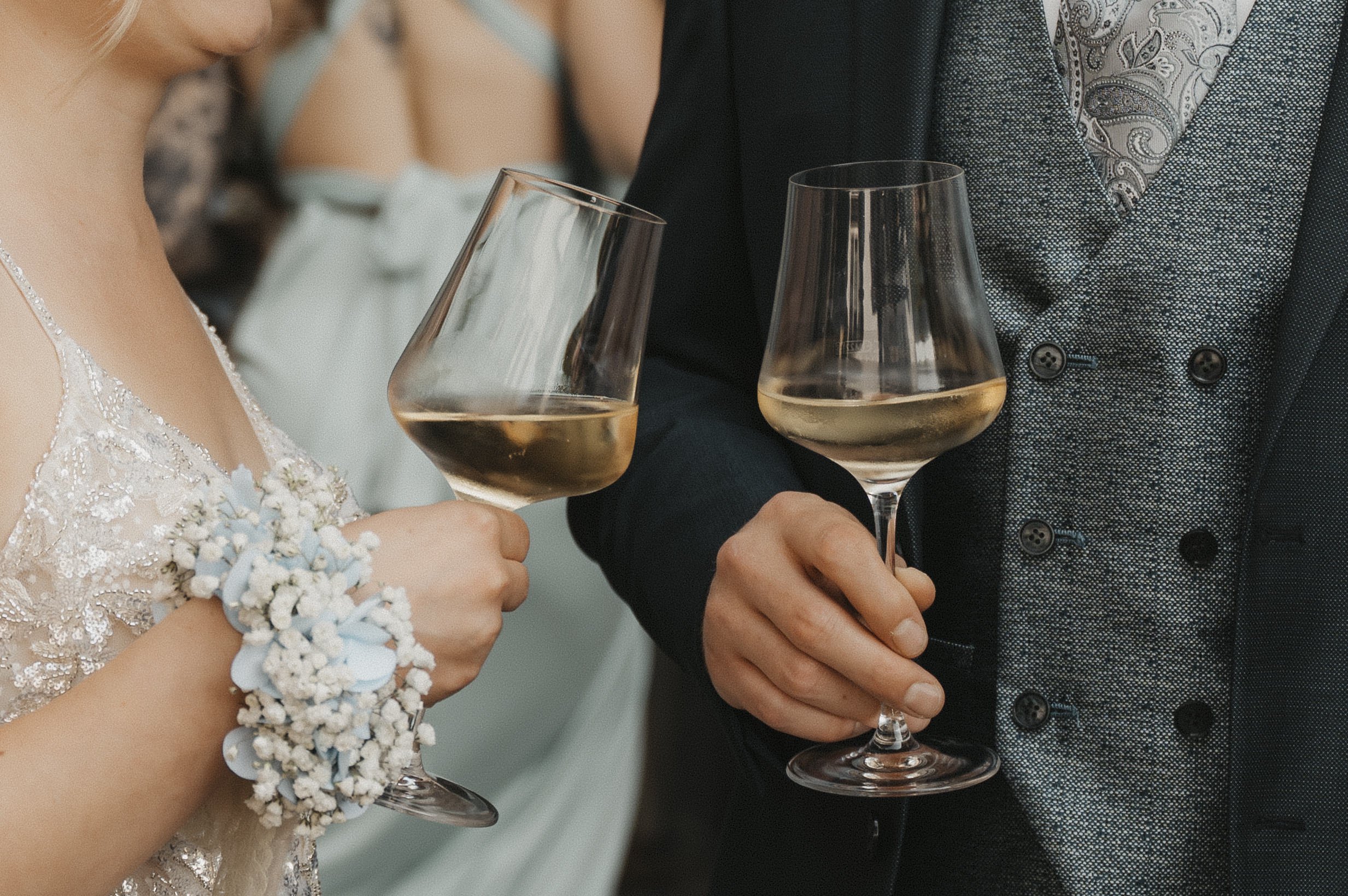 Ein Brautpaar bei einer Hochzeitsfeier, das Wein glasen hält