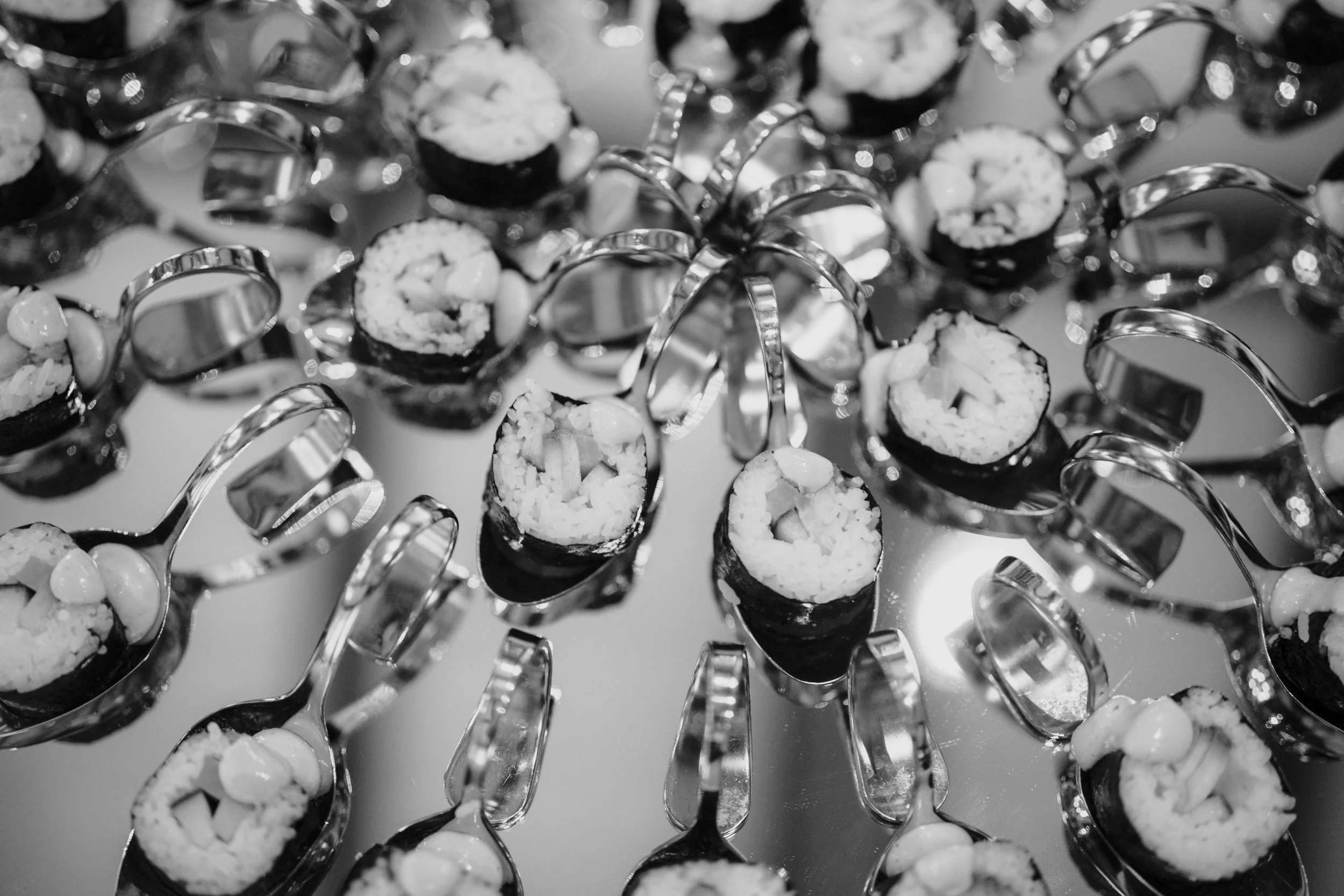 Schwarze Sushi-Rollen mit weißen Füllungen, serviert auf einem spiegelnden Teller.