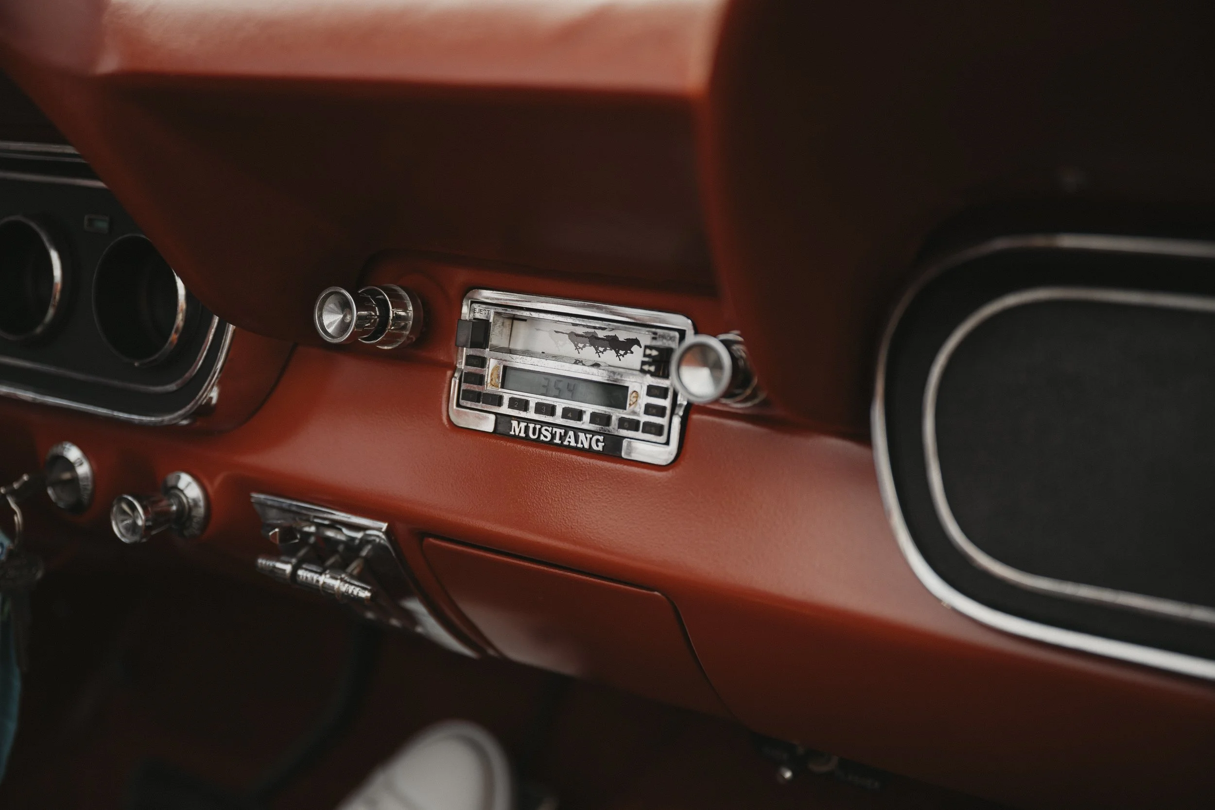 Innenraum eines Ford Mustang, rotes Armaturenbrett mit Radio und Klimasteuerung, schwarz-weißes Design.