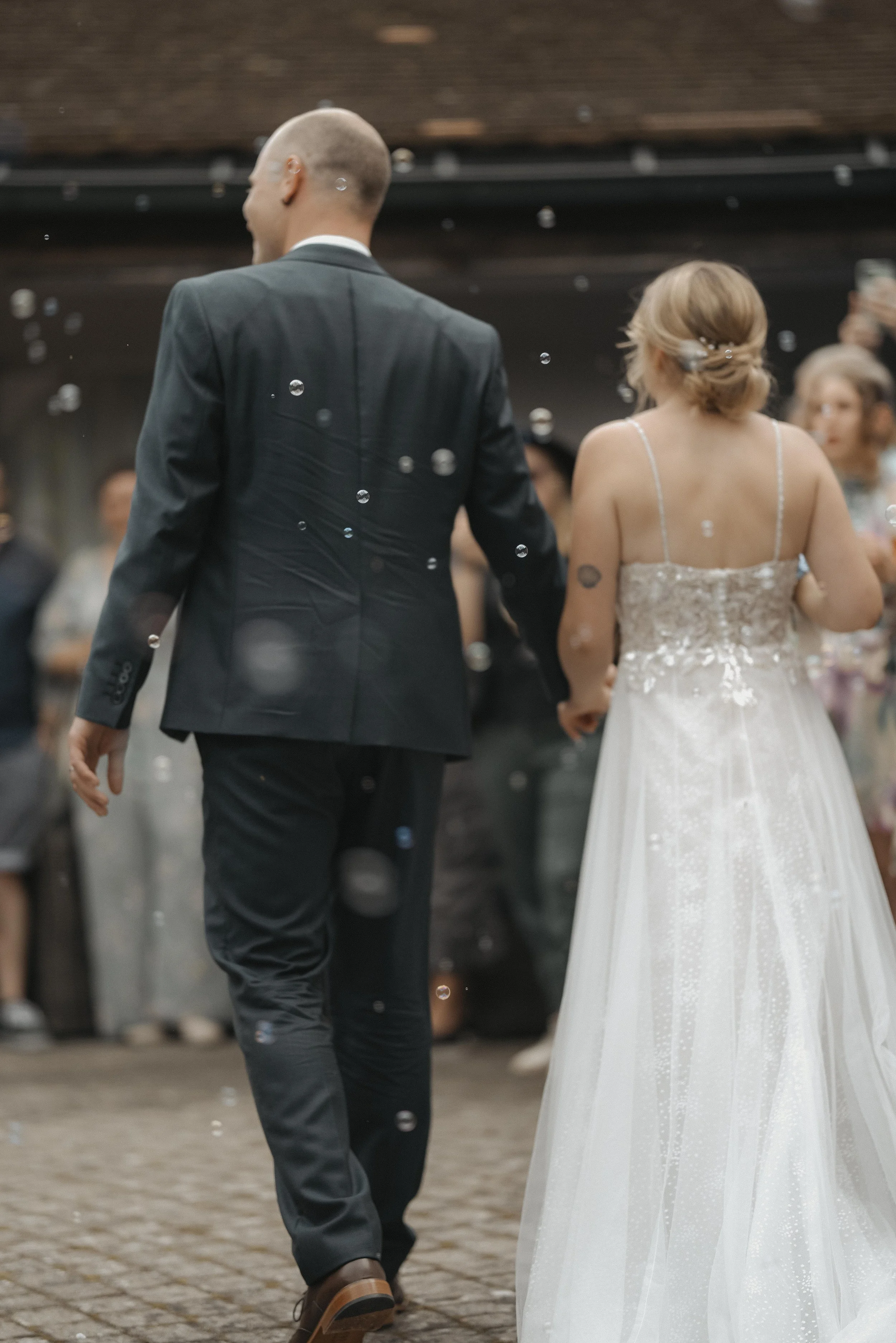 Braut und Bräutigam tanzen bei ihrer Hochzeit, im Hintergrund feiern Gäste.